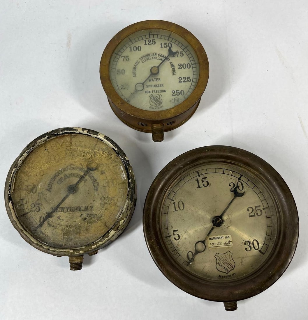 Ashcroft & Automatic Sprinkler Gauges: 5-6 inches. This lot comprises a trio of vintage industrial pressure gauges primarily constructed of brass for use in fire suppression and water systems. The collection includes two specialized