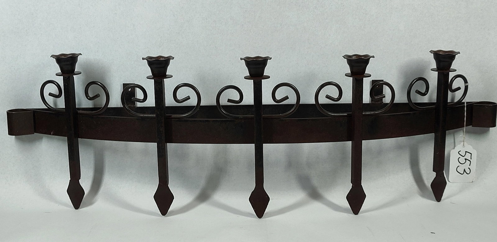 Gothic 5-Light Wrought Iron Wall Sconce: 32 inches. A five-light wall-mounted candle holder constructed from wrought iron with a dark brown patinated finish. The design features a curved horizontal support bar holding five vertical