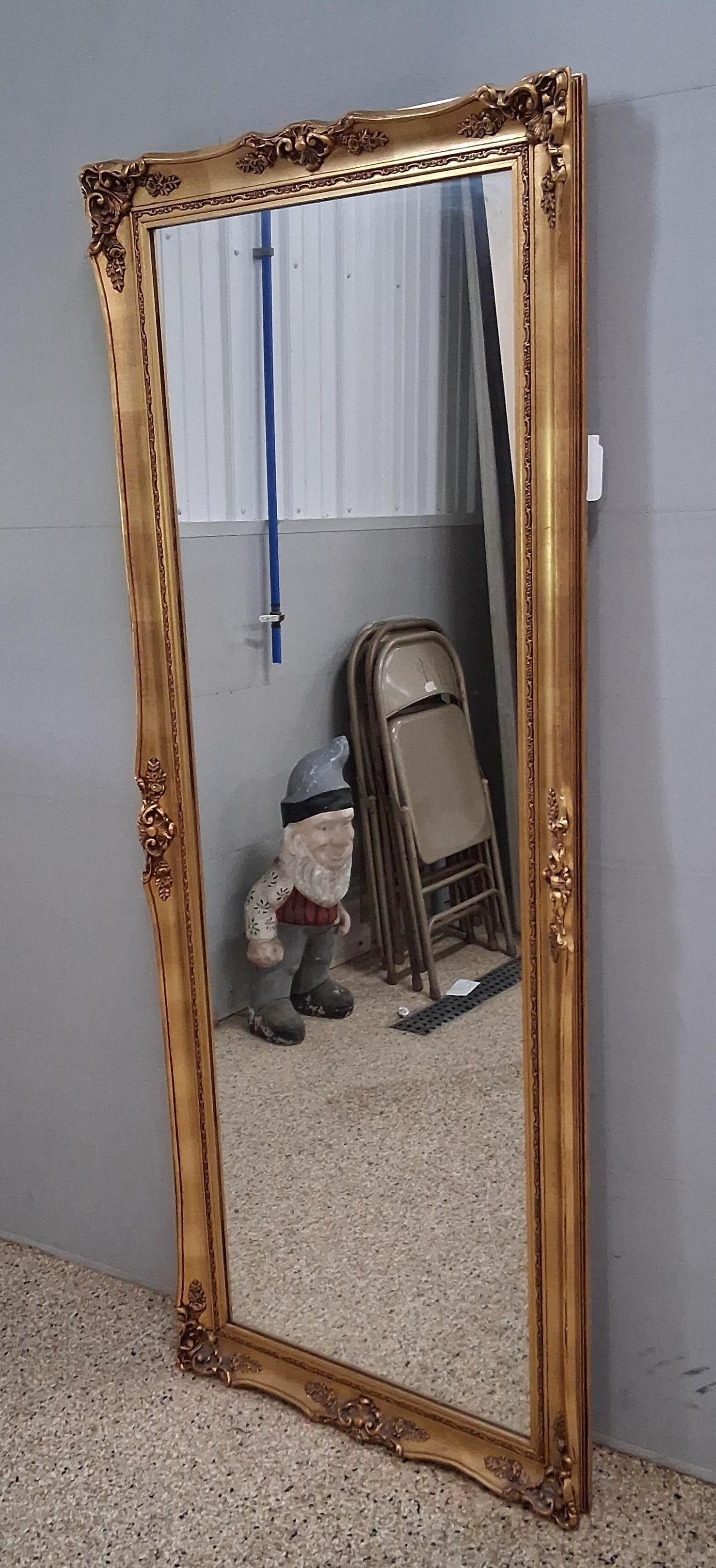 Rococo Revival Gilt Wall Mirror: 25.5x66 A large full length wall mirror designed in the Rococo Revival style. The rectangular frame features an arched crest and is decorated with elaborate molded ornamentation including scrolling