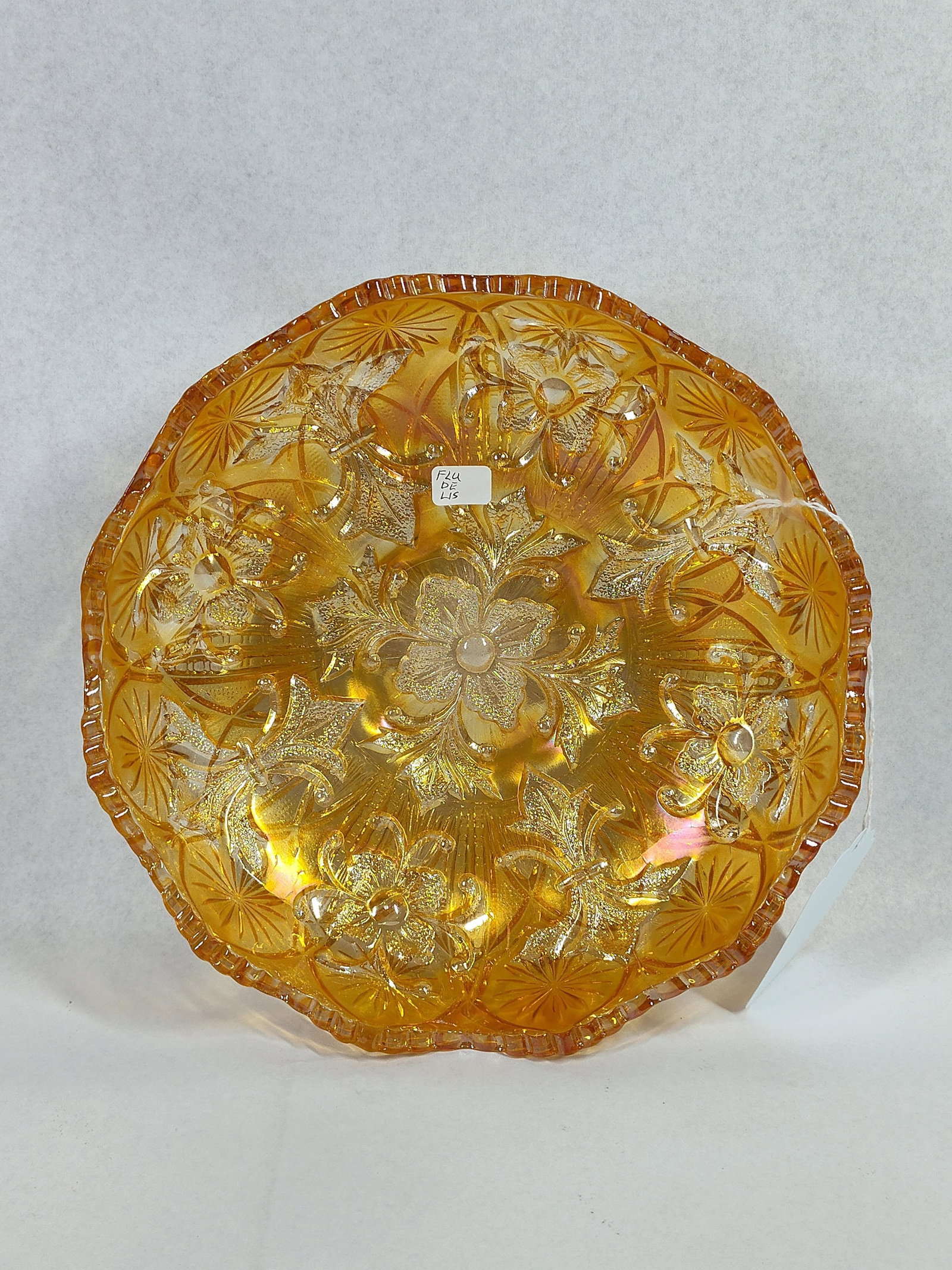Fenton Fleur-de-Lis Carnival Glass Bowl: 9 inches. This Fenton Art Glass Company pressed glass bowl is rendered in the Fleur-de-Lis pattern with a marigold iridescent finish. The interior design features a central multi-petaled flower