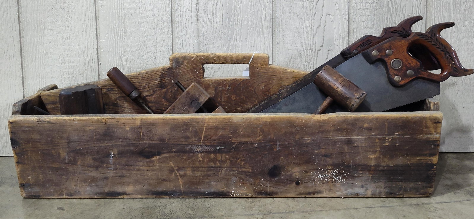 Antique Woodworking Hand Tools & Tote: An assortment of antique woodworking hand tools and a wooden carrier. The collection includes a hand saw featuring a carved wooden handle with a wheat-ear motif and a brass medallion marked Disston,