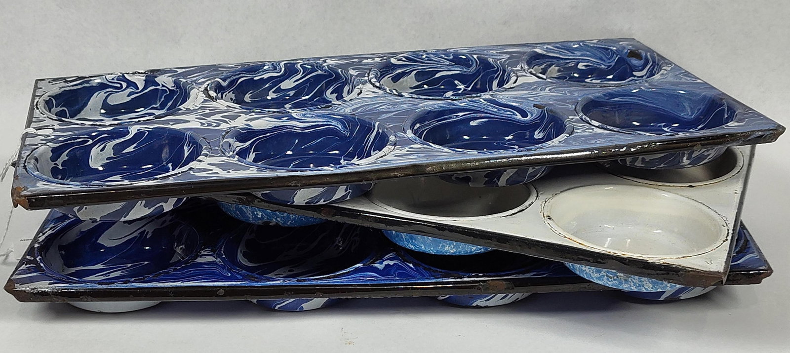 3 Cobalt Swirl Graniteware Muffin Tins: A trio of antique 8-cup muffin tins, also known as gem pans, constructed from stamped sheet metal with a vitreous porcelain enamel coating. The group consists of two pans decorated with a cobalt blue 