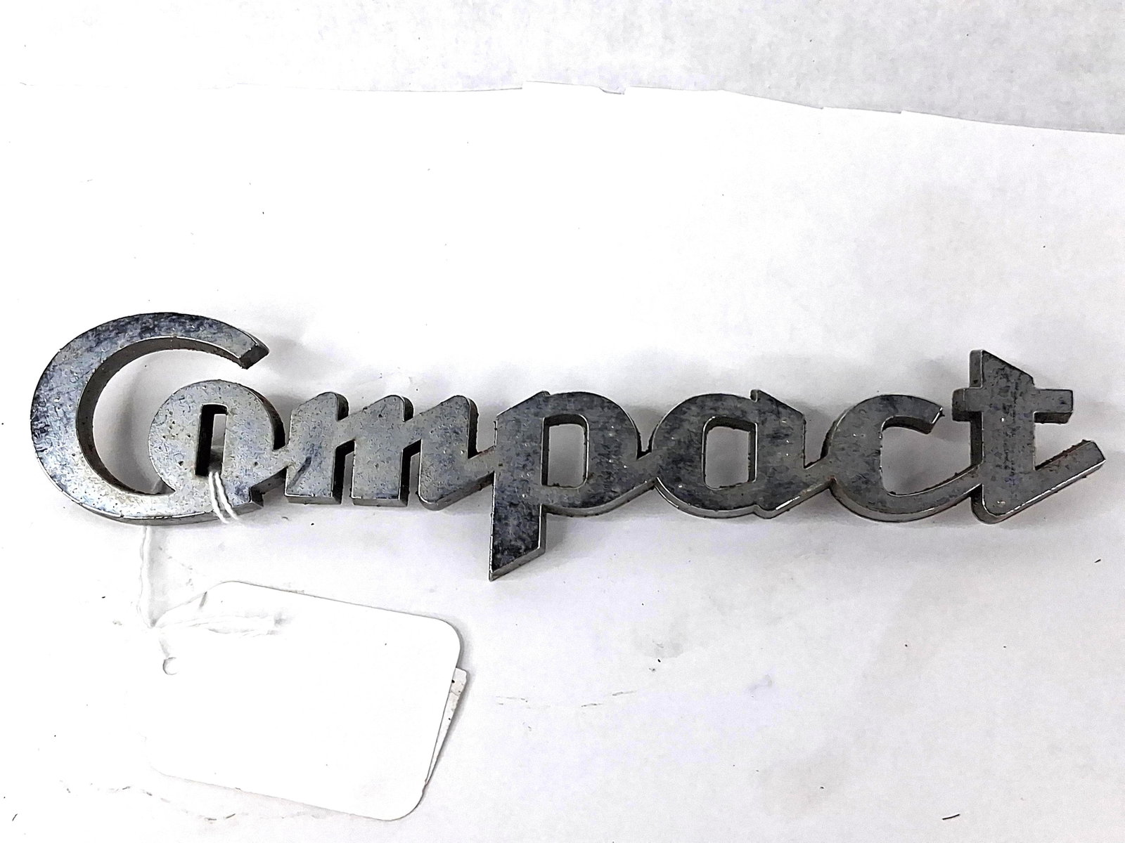 1960s White Motor Co Truck Nameplate: This is an original automotive nameplate emblem from the 1960s, manufactured for use on White Motor Company Compact series trucks. The emblem is a script-style badge featuring the word Compact in a