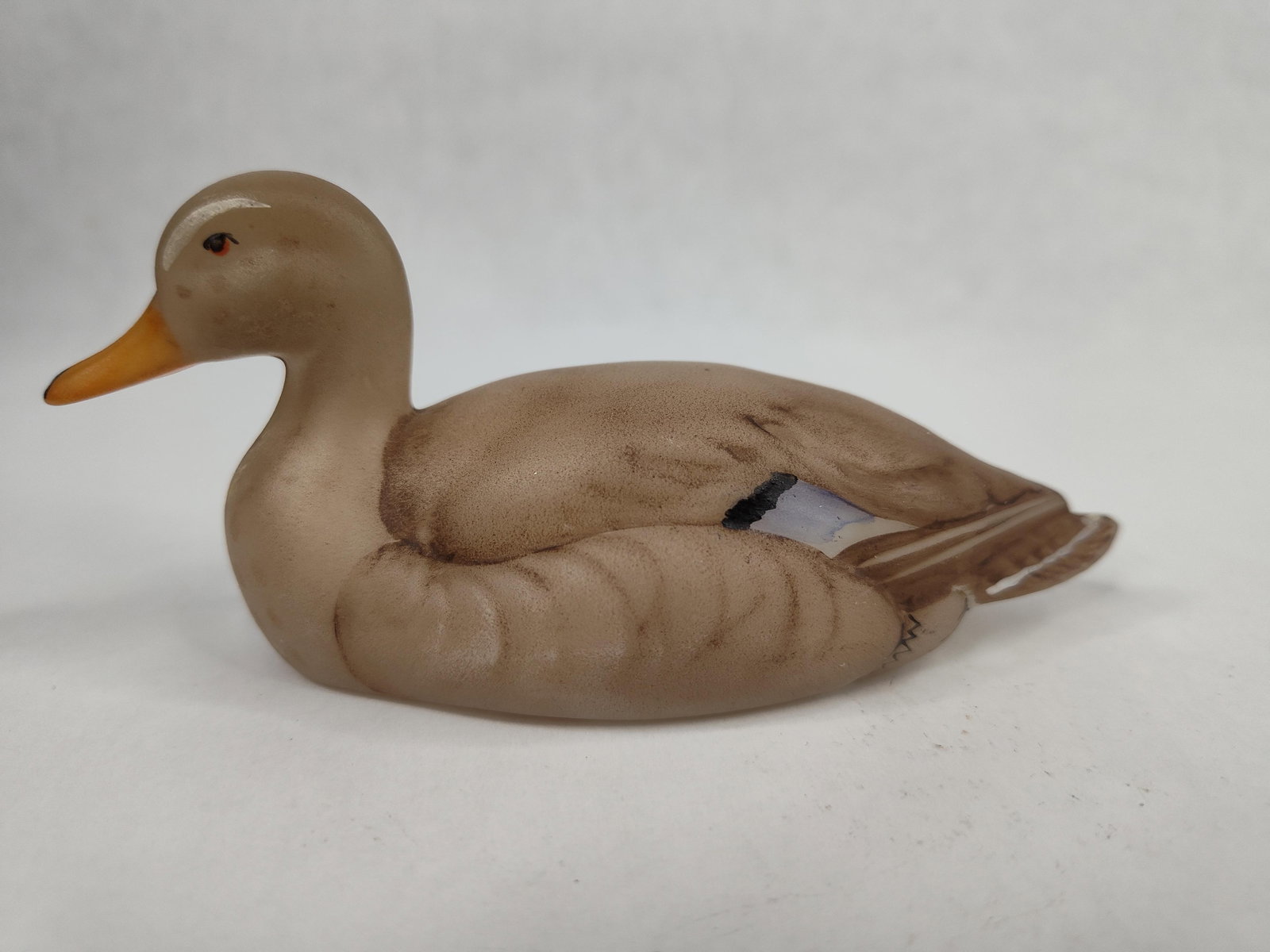 Fenton Mallard Figurine, Marilyn Wagner: Fenton Art Glass hand-painted bisque ceramic figurine of a hen mallard duck. The figurine is modeled in a resting position with a naturalistic finish. The decoration features a tan body with dark