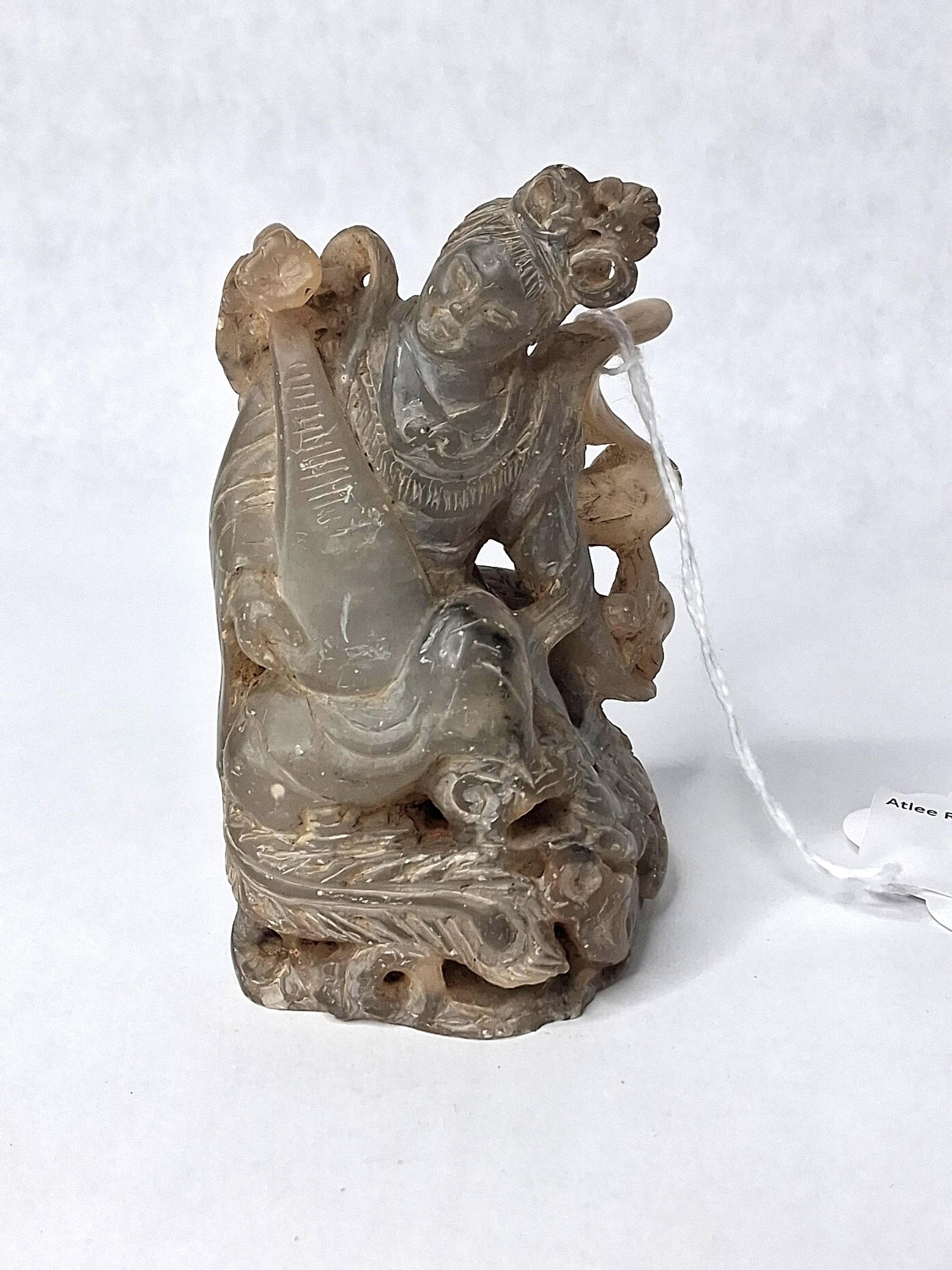 Chinese Jade Celestial Maiden w/ Pipa: A Chinese carved hardstone figure, identified by a base label as jade, portraying a celestial maiden or deity. The seated figure is shown playing a pipa, a traditional Chinese lute. She is dressed in