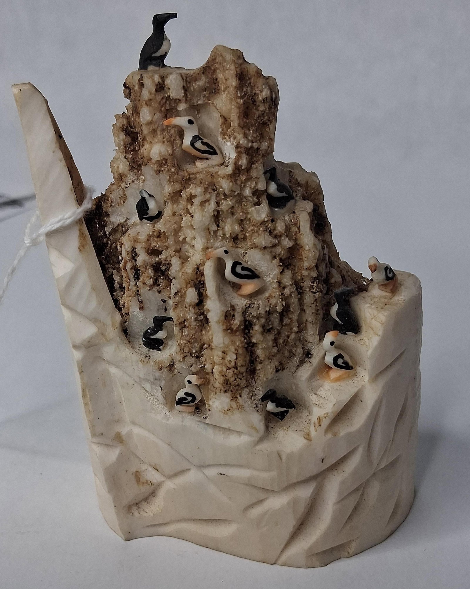 Dominic Mayac Walrus Ivory Bird Rookery: This Alaska Native sculpture is hand-carved from natural material by artist Dominic Mayac of King Island. The work depicts a bird rookery on a cliffside, artistically incorporating different sections