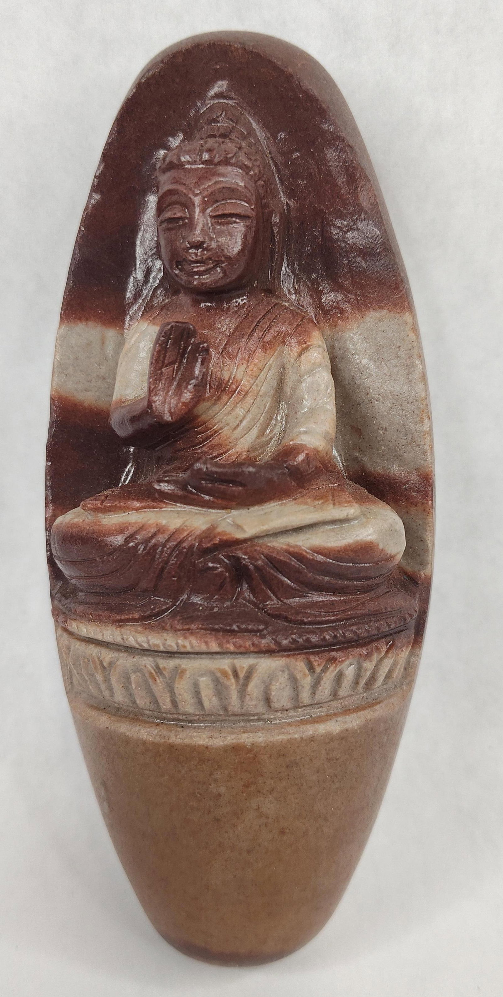 Narmada River Stone Buddha Shiva Lingam: A hand-carved stone sculpture featuring a seated Buddha figure integrated into a naturally formed ellipsoidal stone known as a Narmadeshwar or Shiva Lingam. The object is crafted from polished banded 