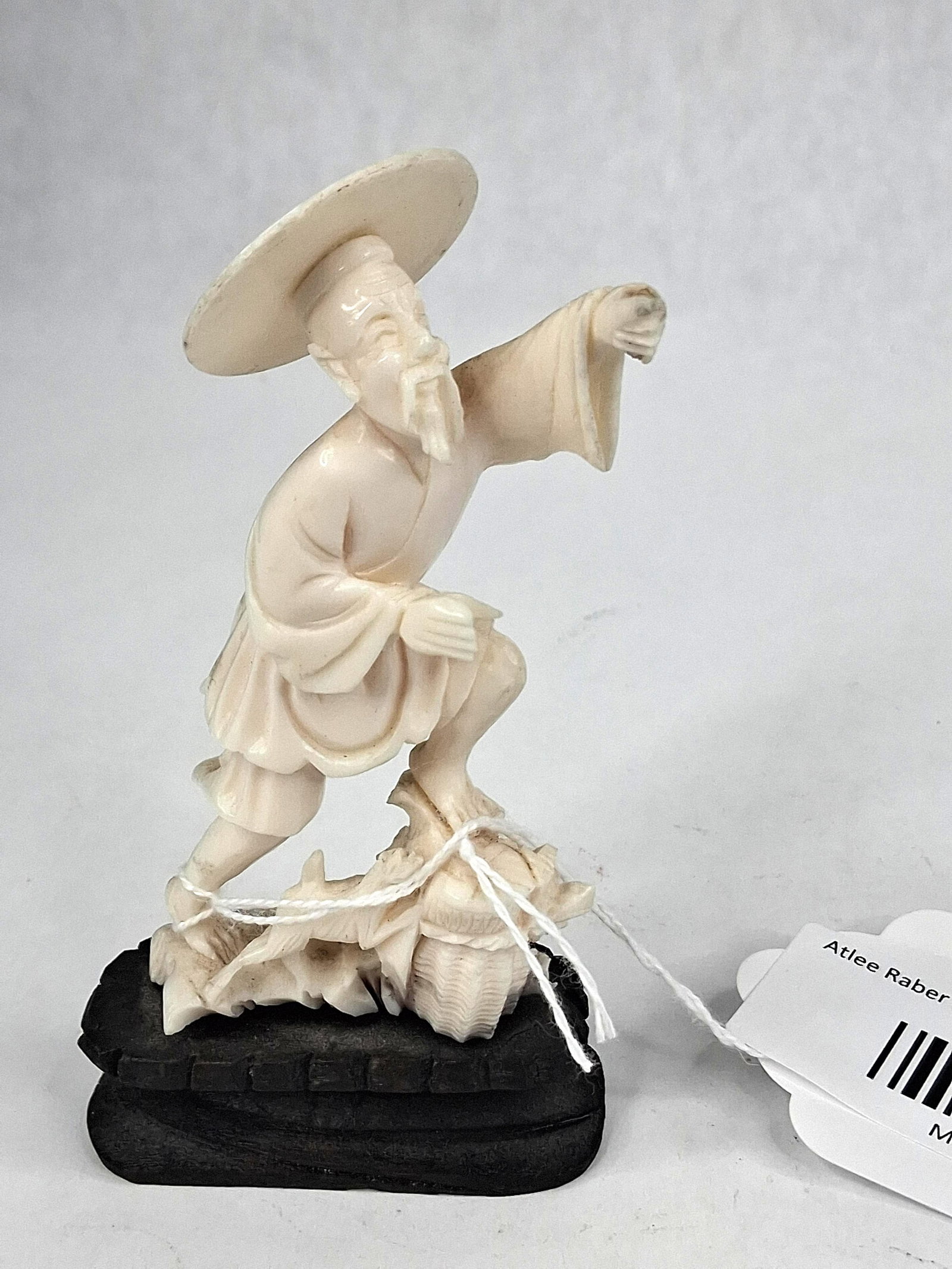 Chinese Carved Bone Fisherman Figure: A hand-carved figurine of an elderly Chinese man, depicted as a fisherman or sage, in a dynamic forward-leaning pose. The figure is dressed in traditional layered robes and a wide-brimmed flat hat,