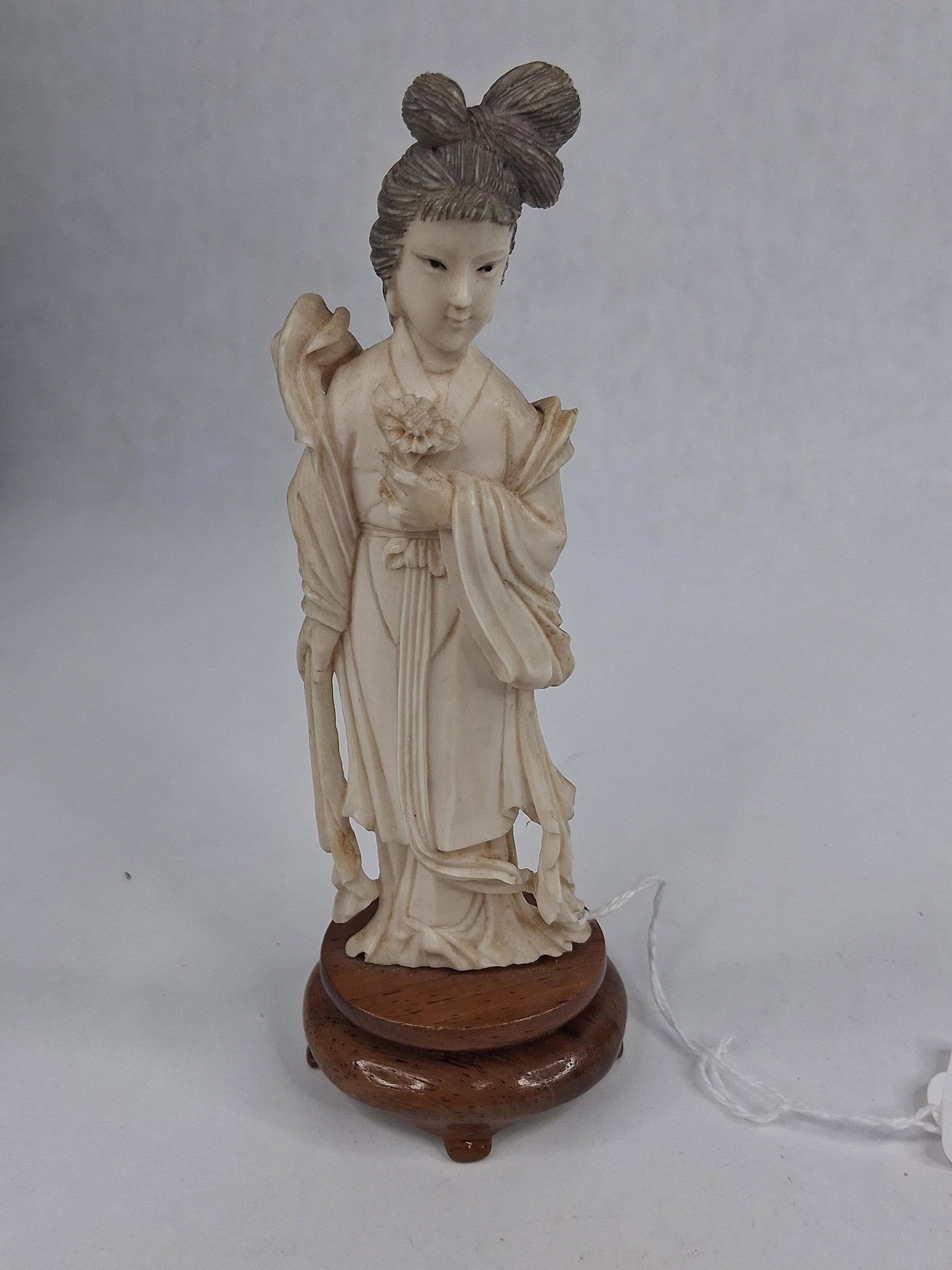 Chinese Bone Woman Figurine w/ Lotus: This is a hand-carved figurine of a Chinese female figure, likely a celestial maiden or the immortal He Xian Gu. The figure is depicted in a standing pose, holding a stylized lotus blossom in her left