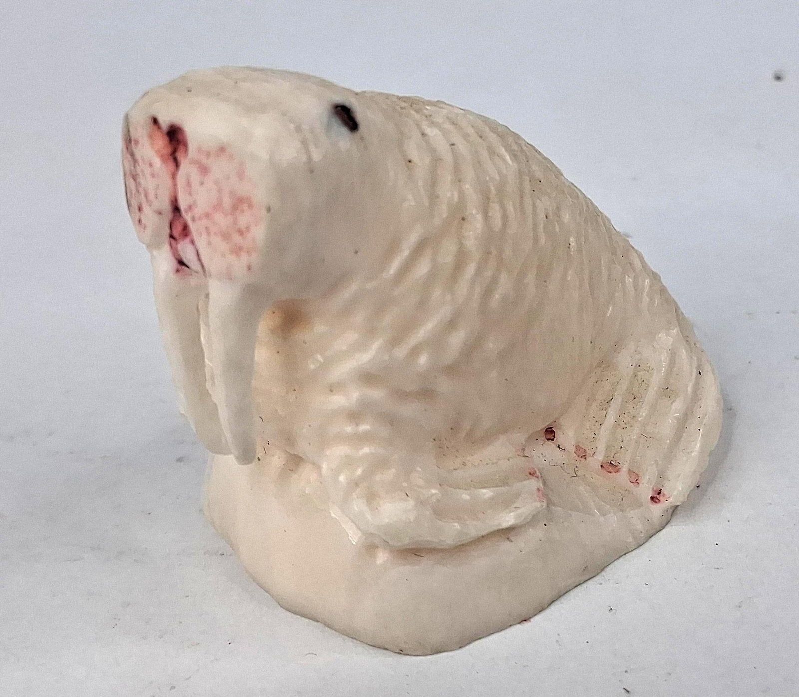 B. Jones Carved Bone Walrus Figurine: A small hand-carved figurine of a walrus in a seated position on an integral base. The piece is crafted from a creamy off-white natural material, such as bone or antler, exhibiting an organic grain