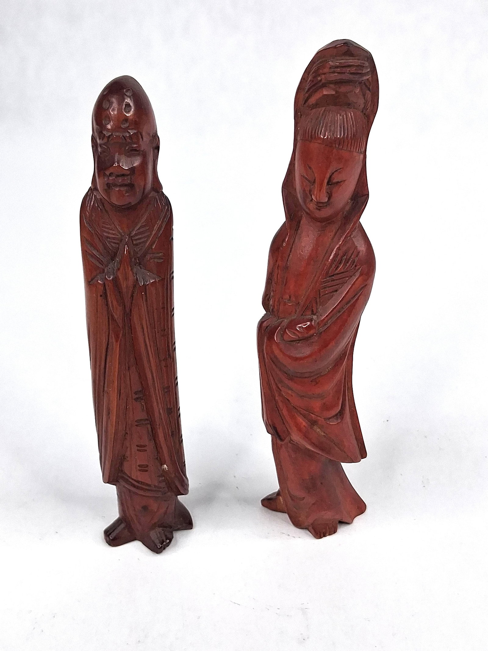 Pair Chinese Boxwood Guanyin & Luohan: A pair of Chinese hand-carved boxwood figures finished in a deep reddish-brown polish. One figure represents the Bodhisattva Guanyin, depicted in an elongated standing pose with a serene facial