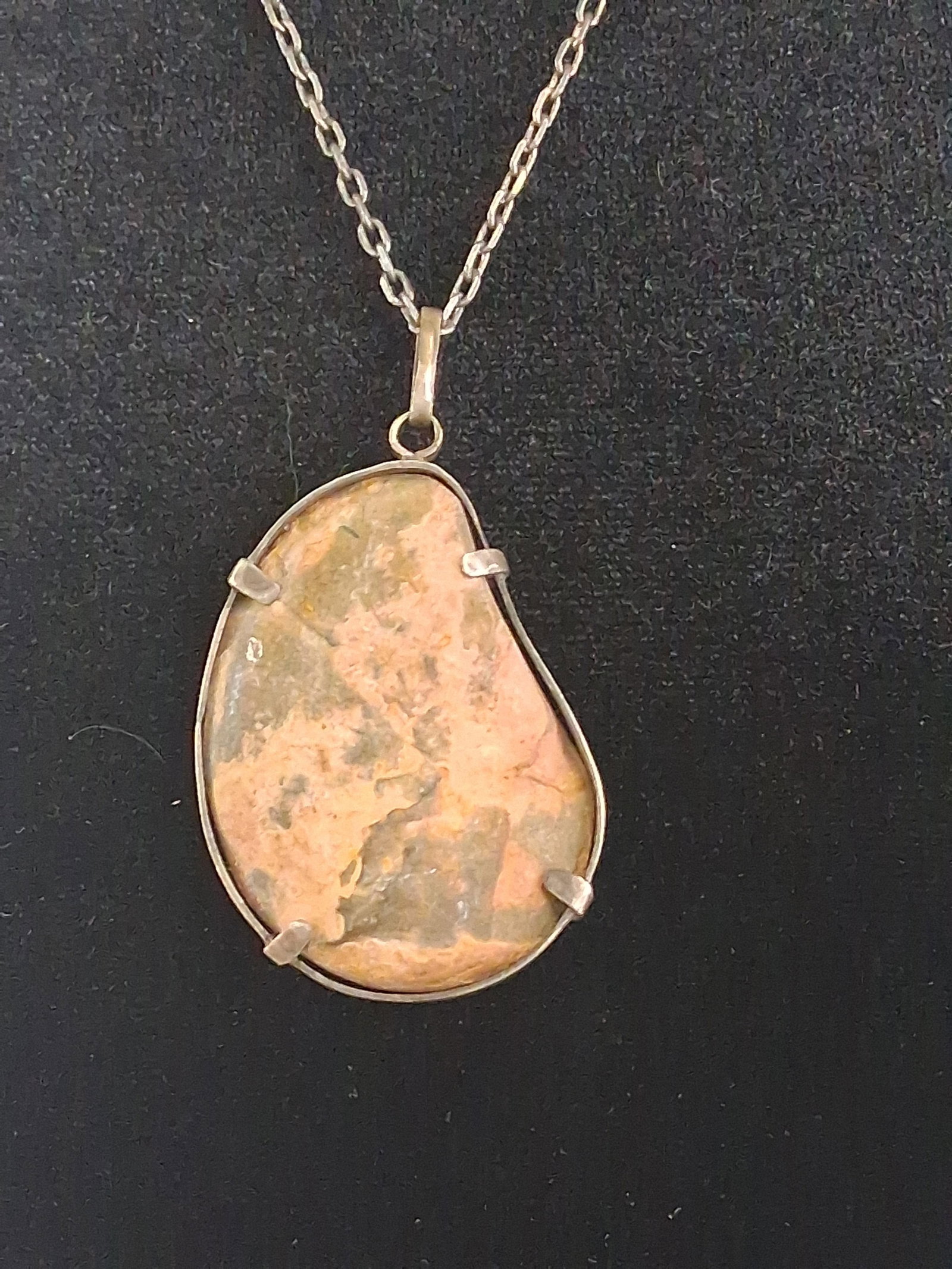 Str. & Ammonite Fossil Pendant Necklace: A sterling silver necklace featuring a freeform pendant containing a polished section of an ammonite fossil set within its natural stone matrix. The double-sided specimen is polished to reveal the int