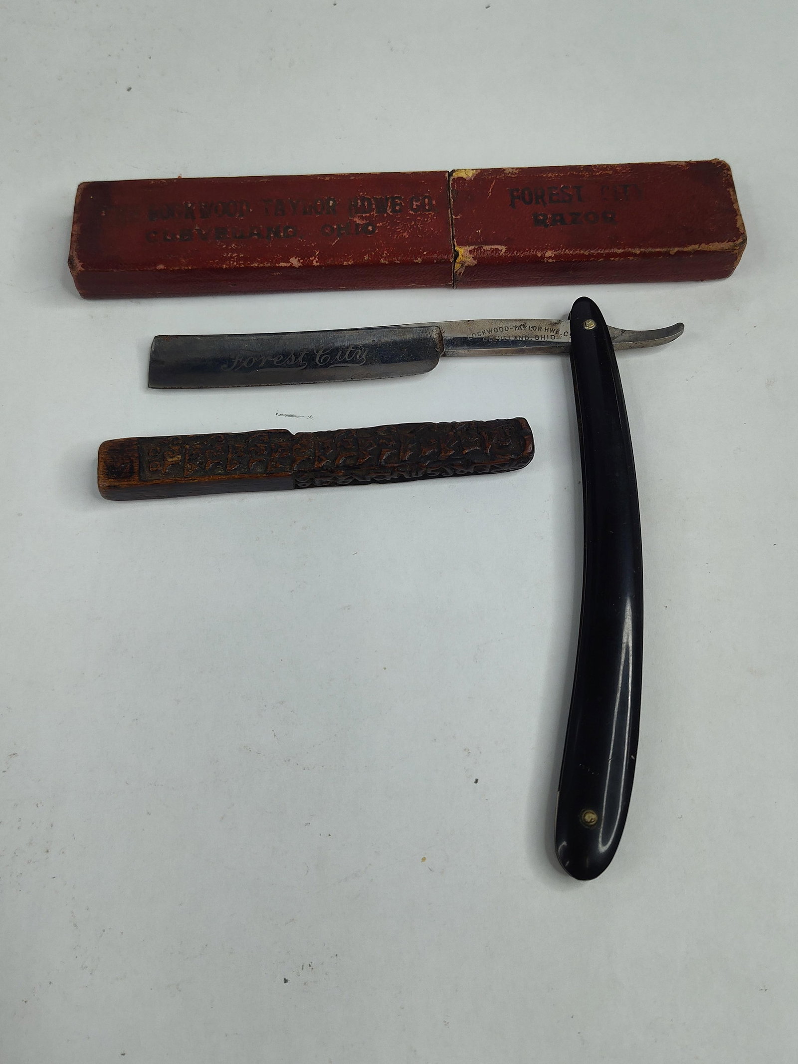 Lockwood-Taylor Razor & Wood Accessory: This lot features a straight razor produced for the Lockwood-Taylor Hardware Co. of Cleveland, Ohio. The carbon steel blade displays a faded acid-etched script reading Forest City on the face. The tan