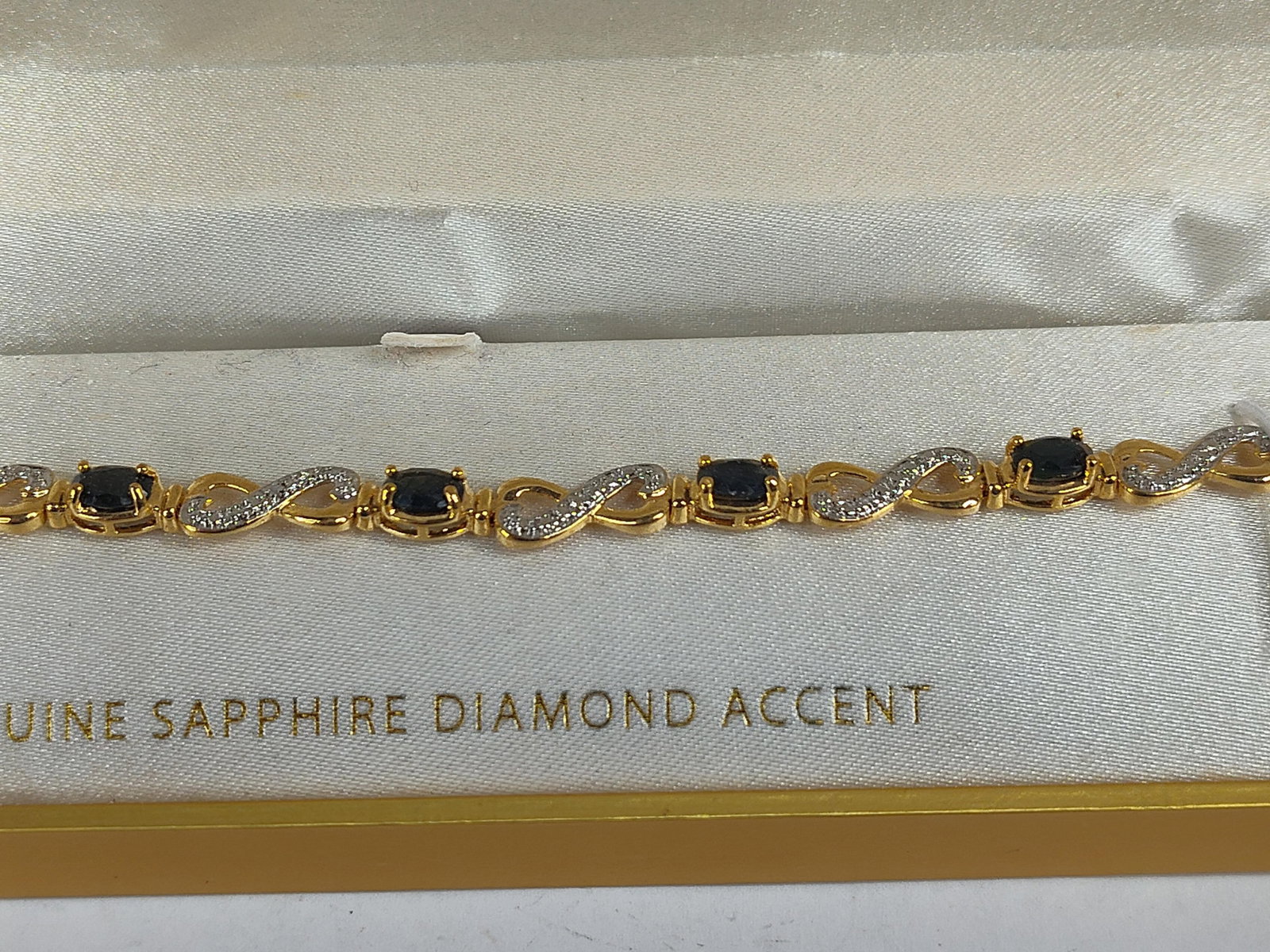 18k Gold/Str. Sapphire Diamond Bracelet: This tennis-style link bracelet is constructed of 18 karat gold plated sterling silver. The design features a series of oval-cut dark blue sapphires, each secured in a four-prong setting. These are co