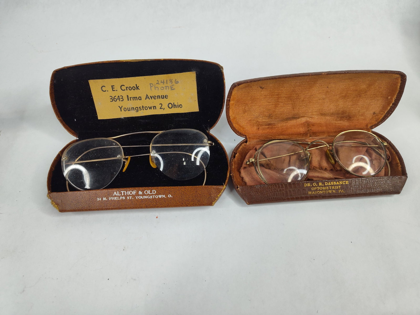 2 Vtg Shuron 12K Gold-Filled Eyeglasses: This lot features two pairs of mid-20th-century American eyeglasses constructed from 12 karat gold-filled metal, accompanied by their respective period hard-shell cases. The first pair is a rimless Fu