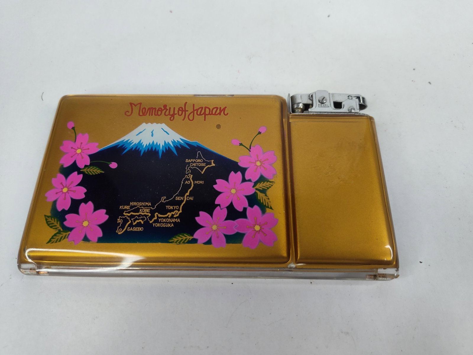 Pearl Cigarette Case & Lighter w/ Box: A mid-century Pearl combination cigarette case and lighter, produced as a souvenir of post-WWII Japan. The rectangular case features a gold-toned finish protected by clear acrylic panels. The front is