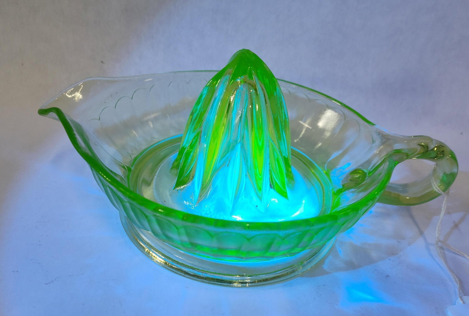 Vtg Green Uranium Glass Citrus Reamer: This citrus juicer, or reamer, is constructed from pressed uranium glass, also known as vaseline glass. The material contains uranium dioxide, giving the piece its characteristic transparent light