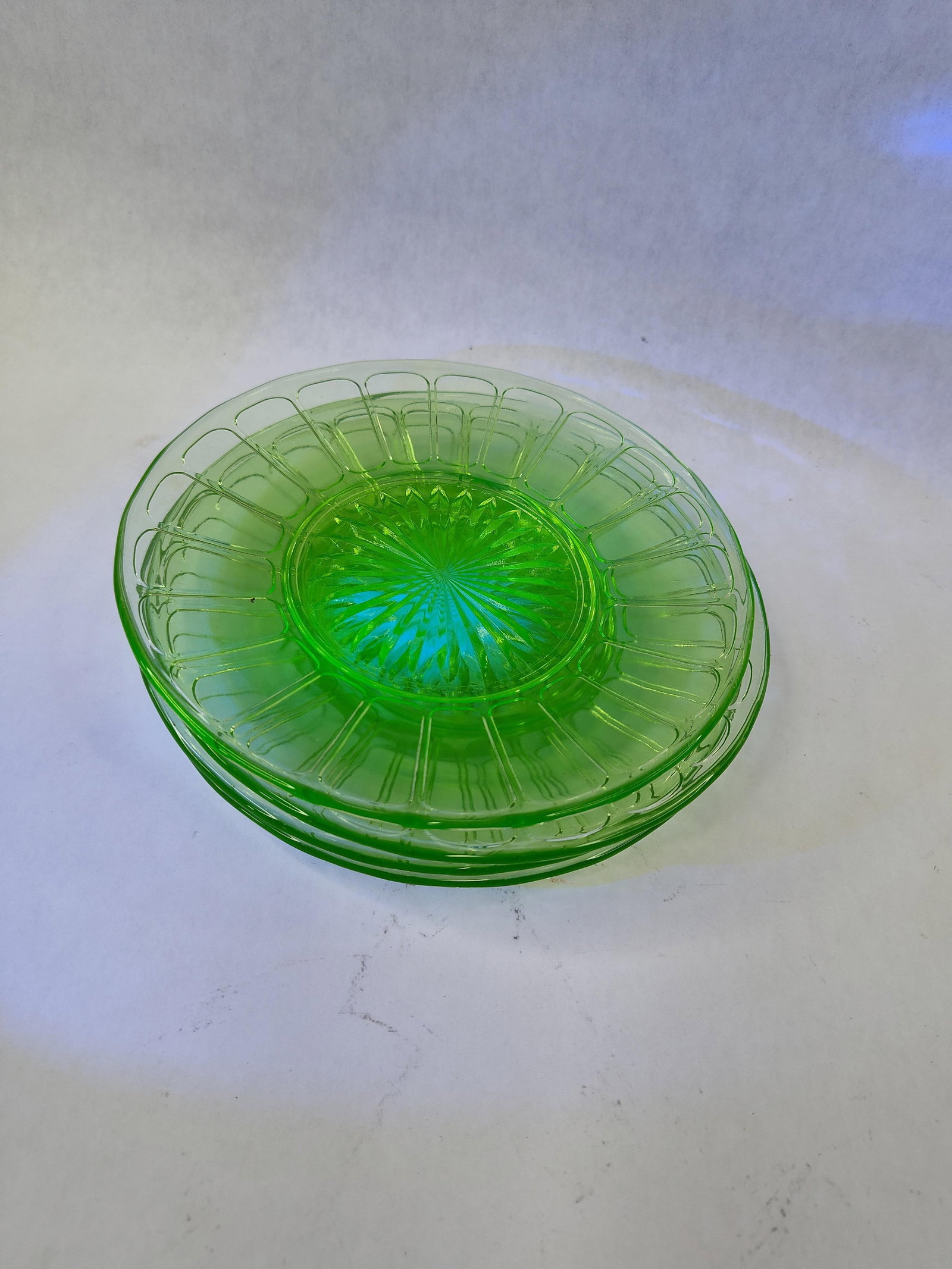 Set 4 Federal Glass Coronation Plates: This set of four transparent green plates is composed of uranium depression glass. The items feature the Federal Glass Company Coronation pattern, defined by a central starburst motif and a wide rim