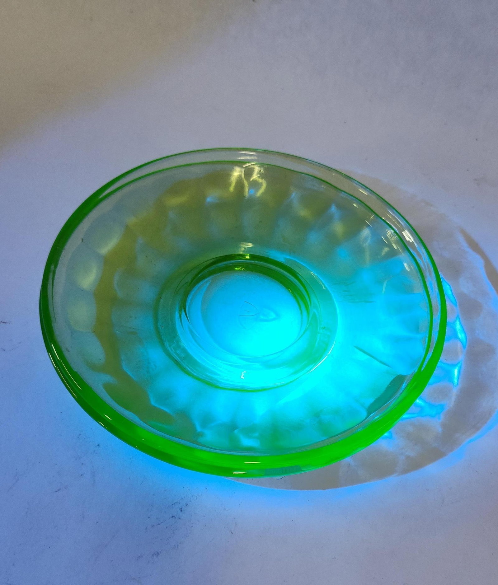 Pair Diamond Uranium Thumbprint Saucers: This pair of transparent light green saucers is crafted from uranium glass, a type of Depression-era glass that contains uranium oxide, causing the pieces to glow bright green under ultraviolet light.