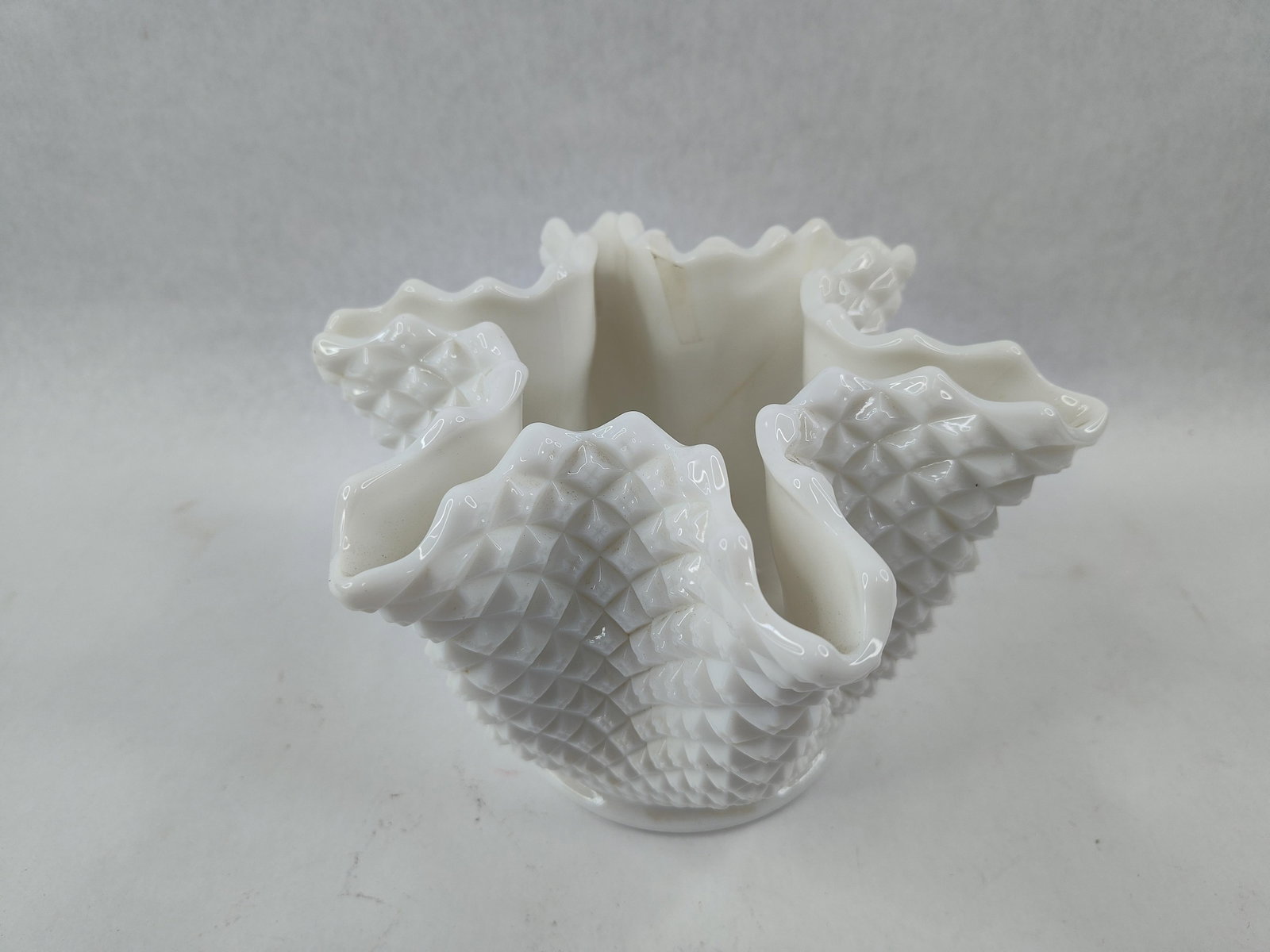 Westmoreland Hobnail Handkerchief Vase: This small decorative vessel is a Westmoreland Glass Company handkerchief vase in the English Hobnail pattern. Crafted from opaque white milk glass, the piece features a dense diamond point relief