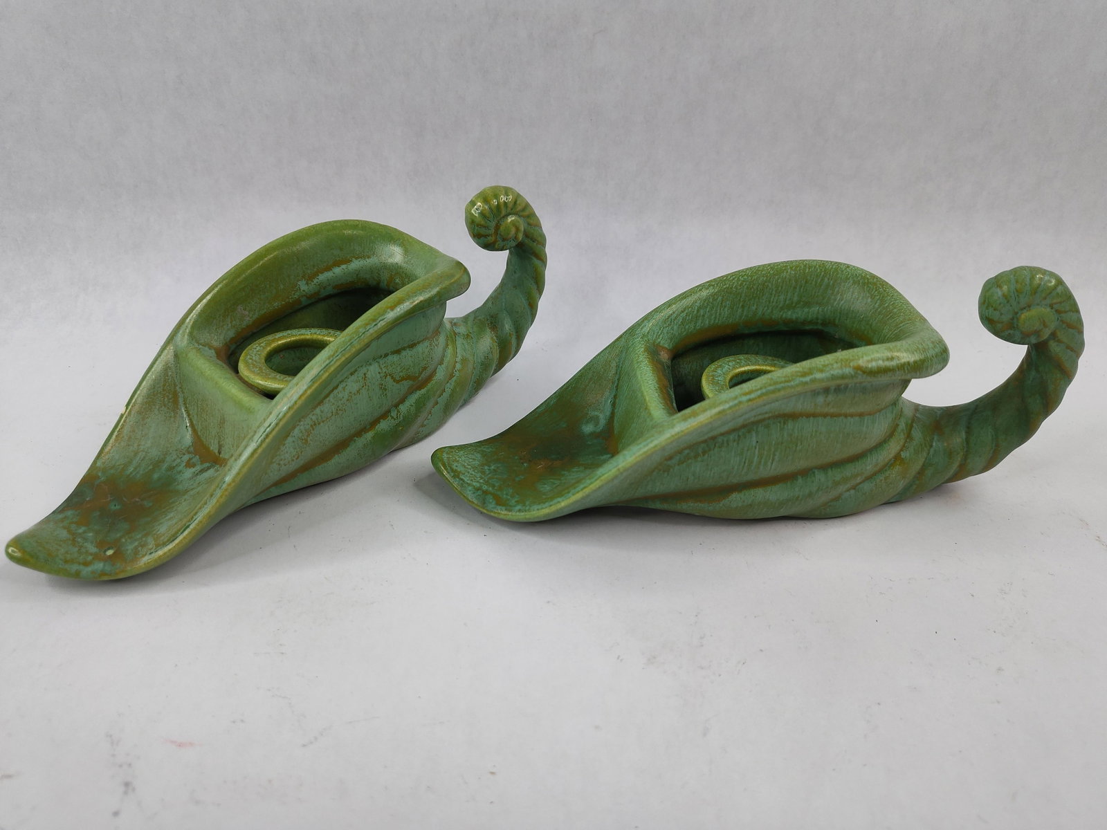 Pair Royal Haeger Cornucopia Holders: A pair of earthenware candle holders produced by Royal Haeger, featuring a stylized cornucopia or curled leaf form. Each piece terminates in a scrolled fiddlehead handle and opens into a wide,