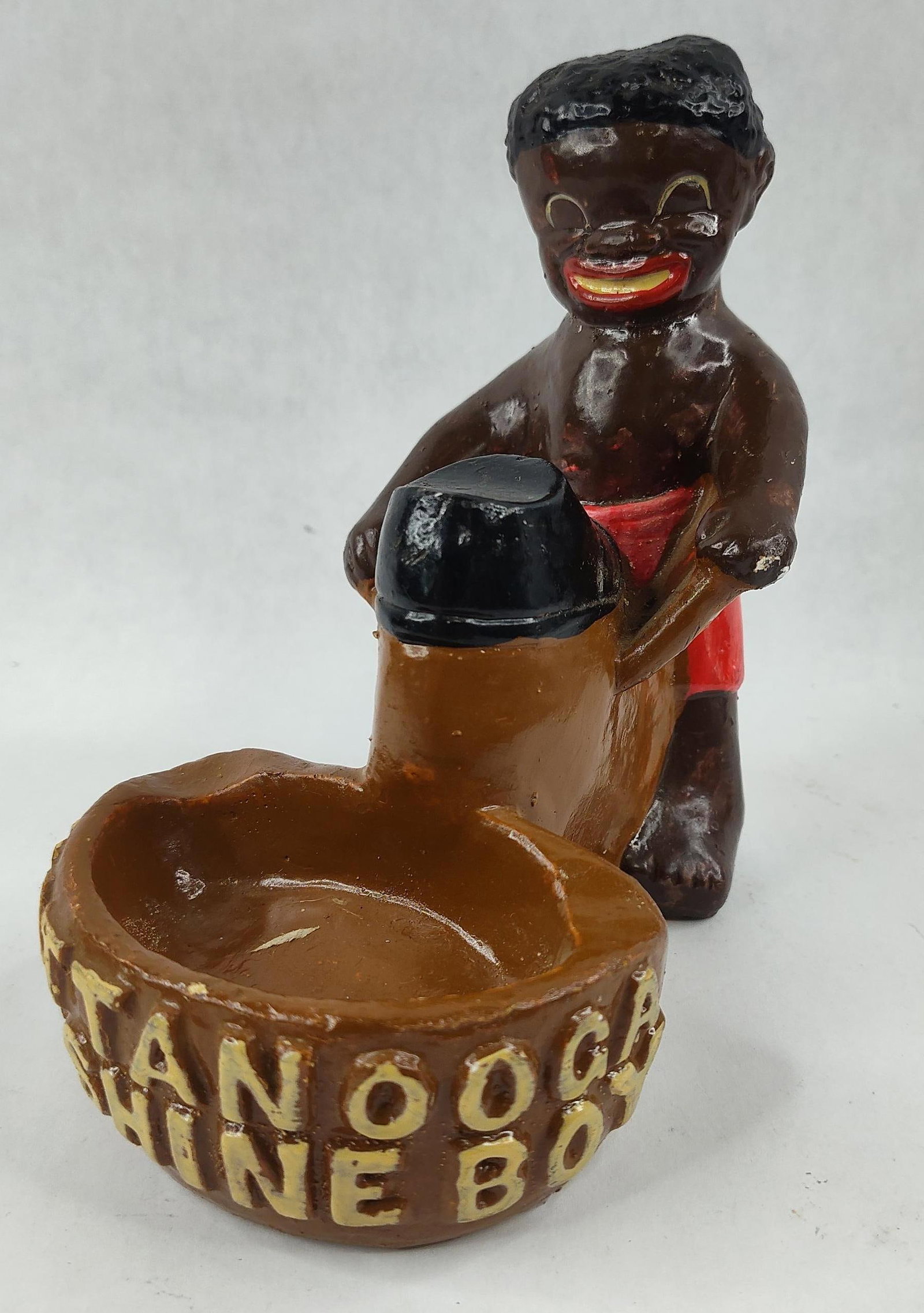 Black Americana Shoe Shine Boy Ashtray: This novelty figurine and ashtray is an example of mid-20th-century Black Americana memorabilia, inspired by the 1950 popular song. The piece is constructed from molded chalkware, a material