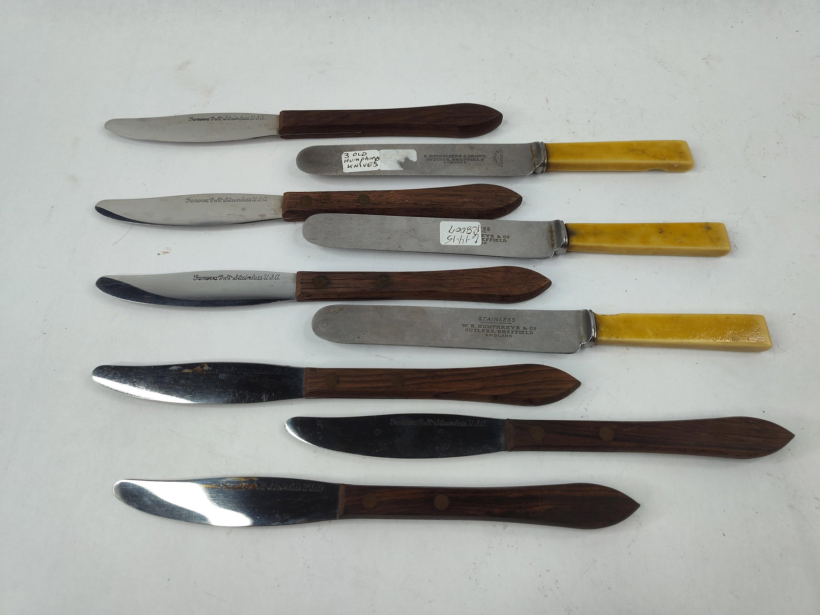 9 Geneva Forge & Sheffield Steel Knives: This collection of nine knives features a combination of American and English cutlery. Six steak knives are marked Geneva Forge Stainless U.S.A. with a pictorial mark of a figure at an anvil. These