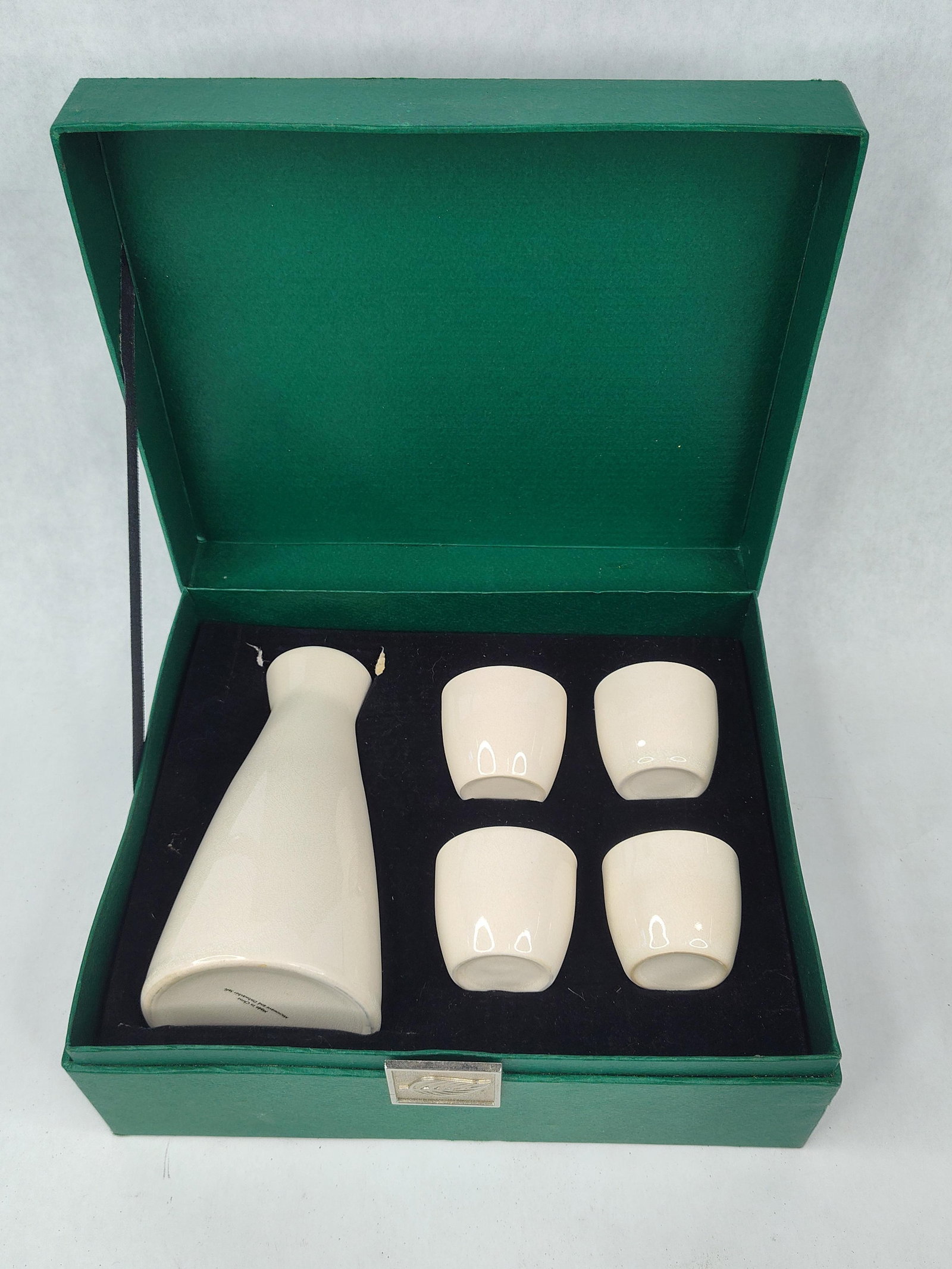 5-Piece Ceramic Sake Set w/ Box: This ceramic sake set is finished in a cream-colored glaze with an intentional fine-mesh crackle pattern throughout. The set consists of one tapered flask and four matching small cups. The flask featu