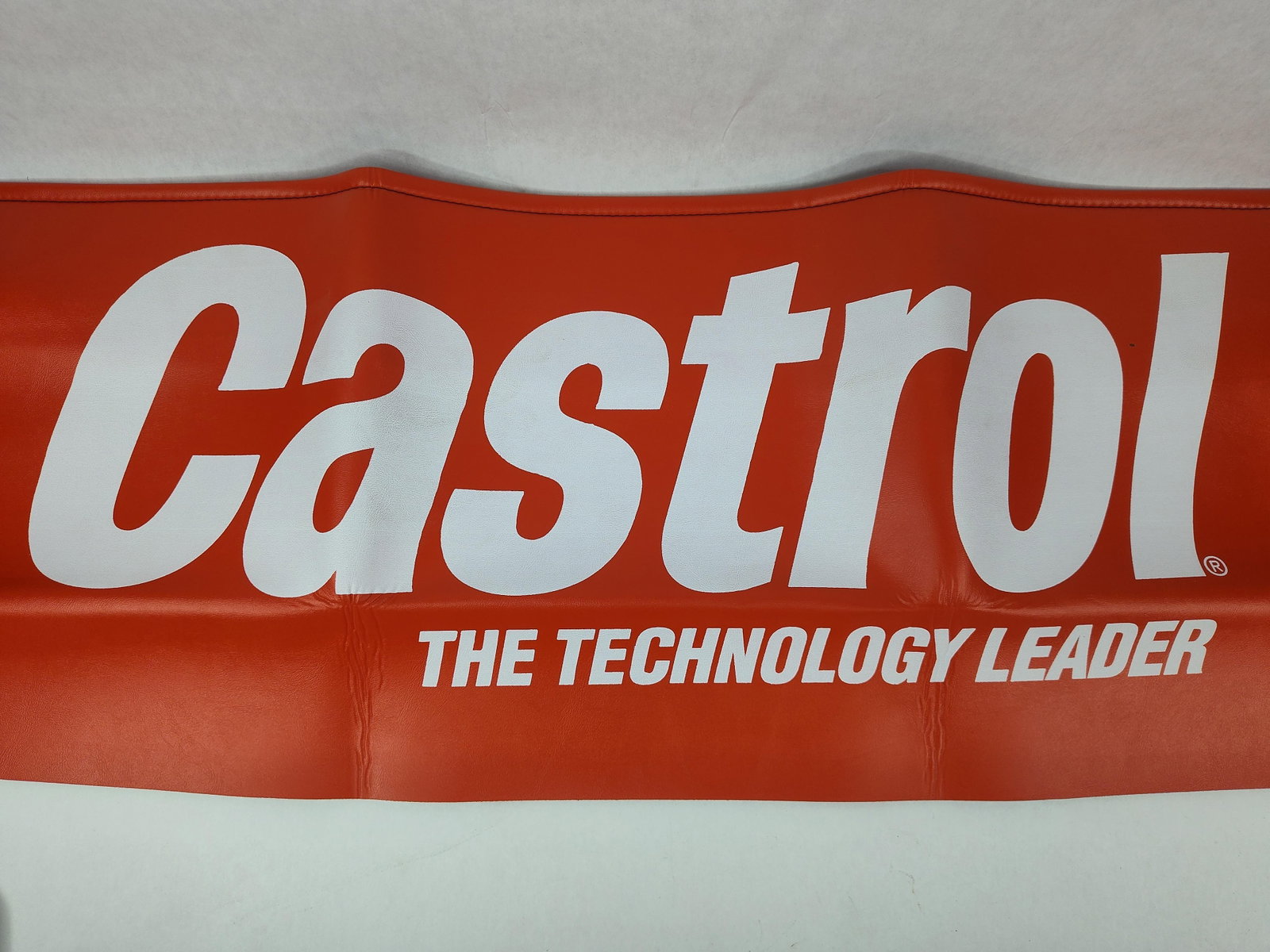 Vtg Castrol Motor Oil Fender Cover: This automotive fender cover features branding for Castrol motor oil. The protective shop mat is constructed from padded vinyl with a red finish on the front and a textured, non-slip black backing.
