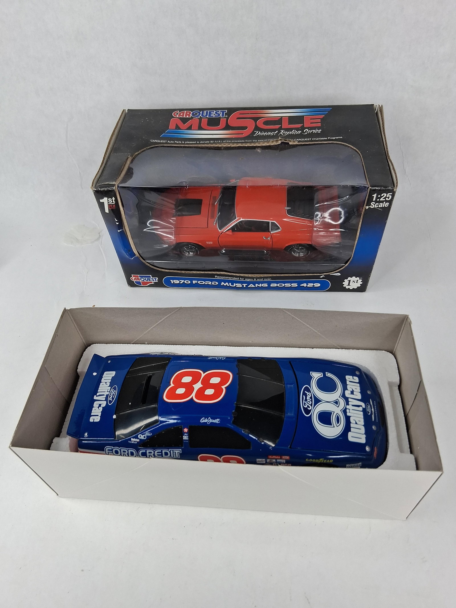 Pair Ford Die-Cast: Mustang & NASCAR: This lot features two die-cast model Ford vehicles in their original packaging. The first is a 1:25 scale 1970 Ford Mustang Boss 429, distributed by CarQuest as part of the Muscle Diecast Replica Seri