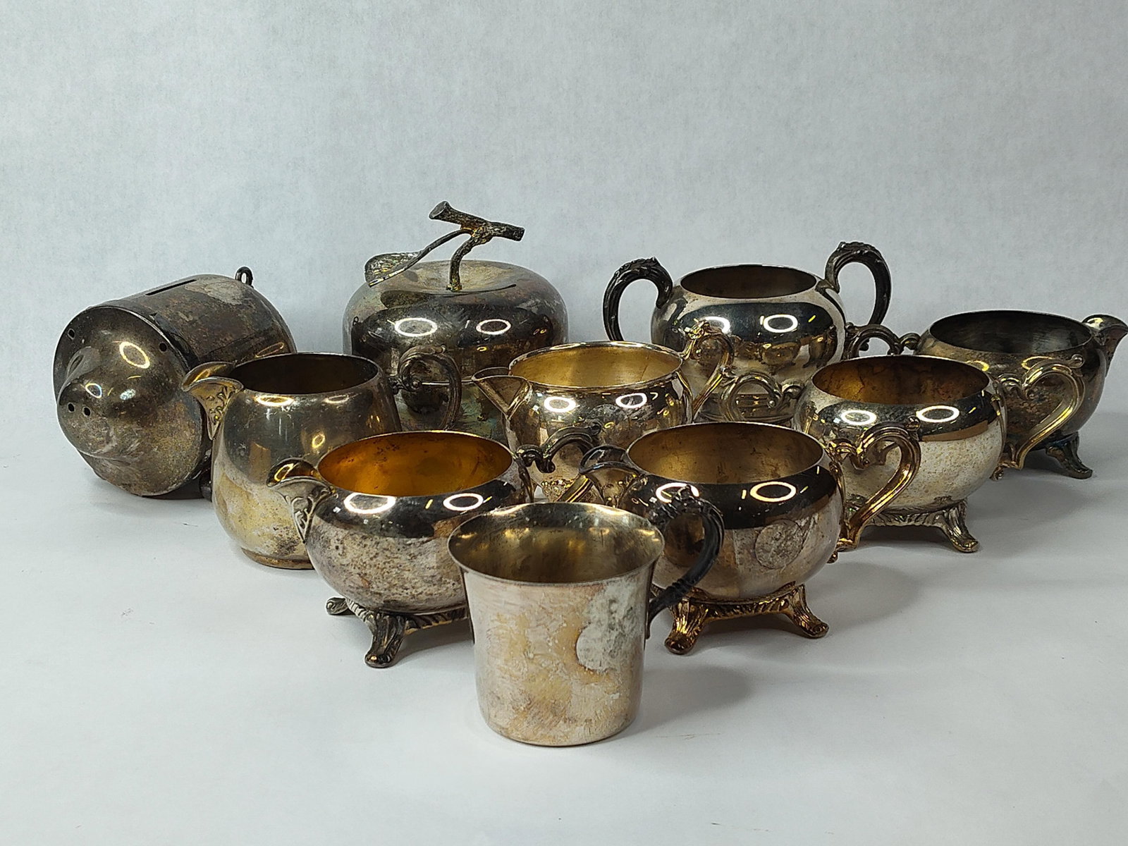 Oneida, Gorham & Wallace Hollowware: An assortment of silver-plated hollowware and novelty items from several prominent American manufacturers. The group includes a figural piggy bank stamped Oneida Silversmiths on the underside. A lidde
