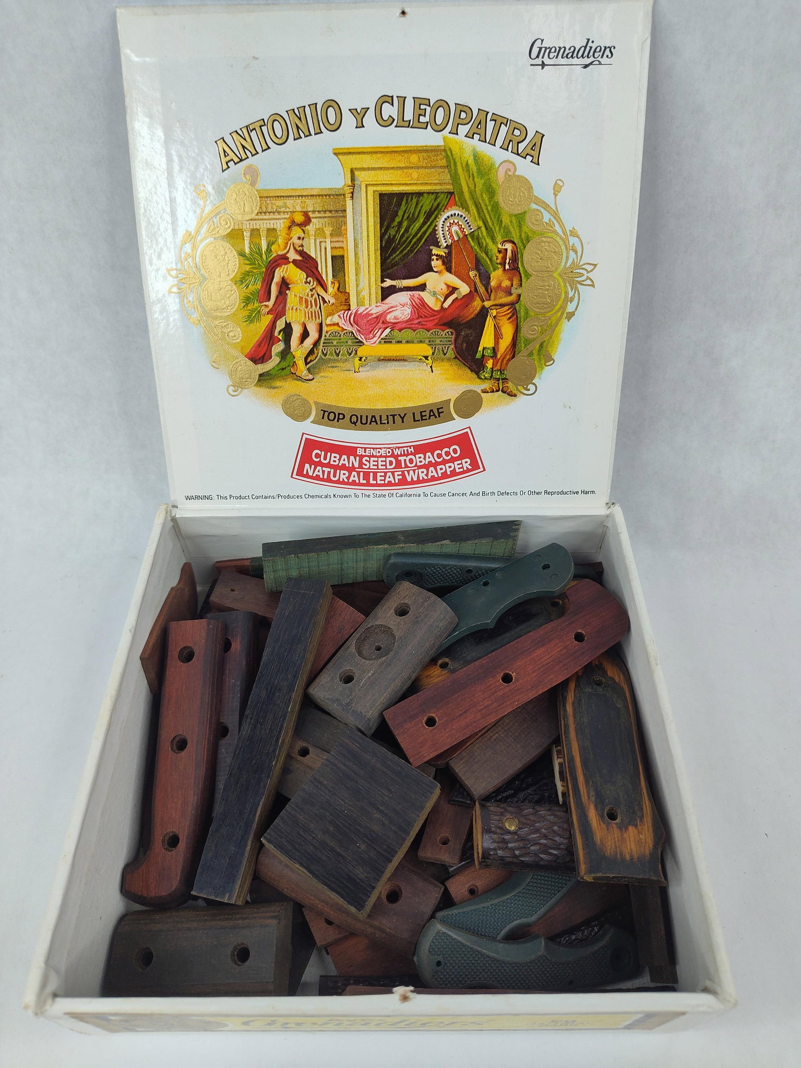 Knife Handle Scales/Blanks in Cigar Box: An assortment of knife-making components and materials featuring various handle scales and blanks. The collection includes wooden handle scales in multiple species, such as rosewood and ebony-toned ha