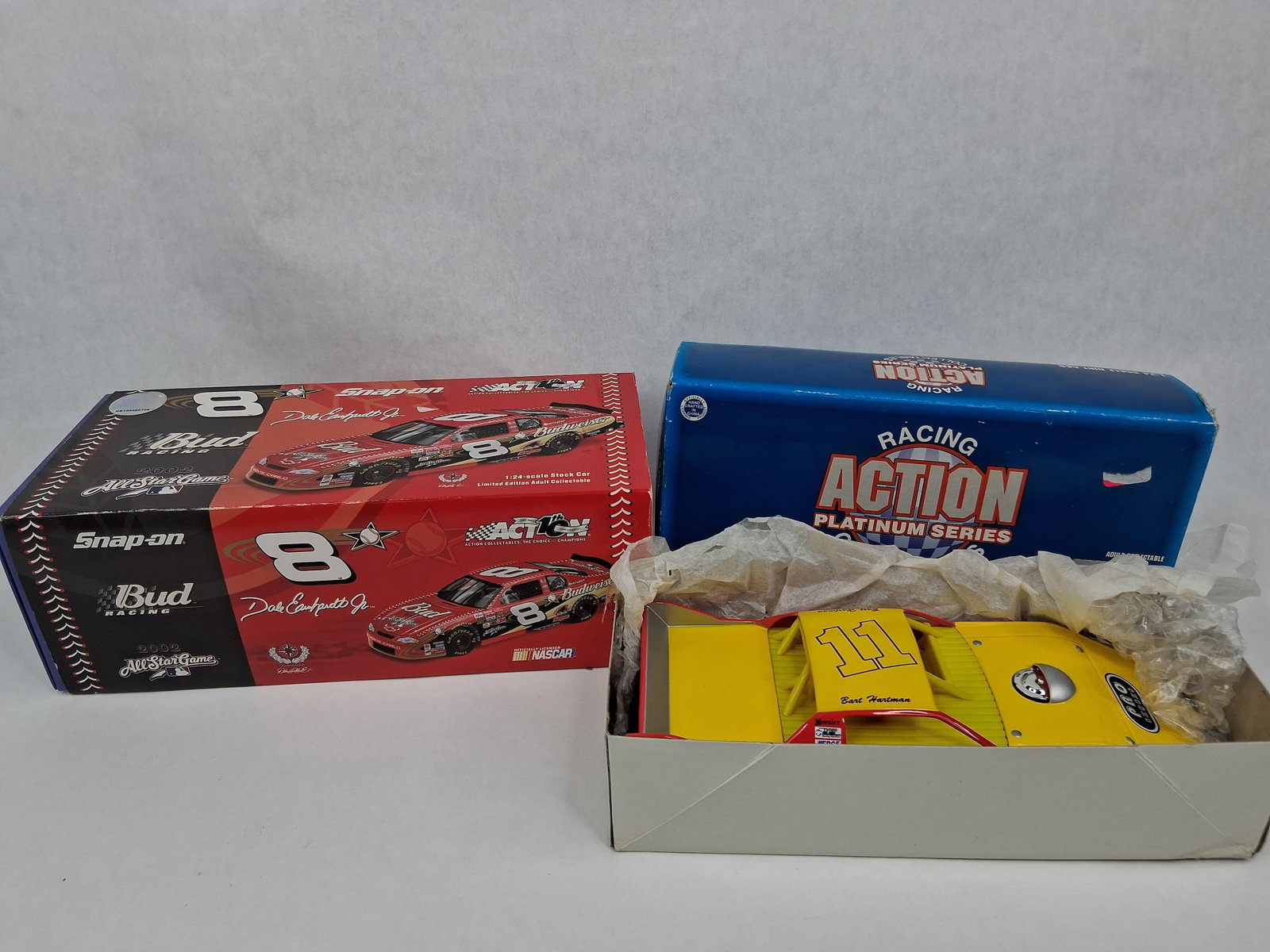Pair Action Racing 1:24 Die-Cast Cars: This lot features two 1:24 scale die-cast model racing cars produced by Action Racing Collectables. Both items are presented in their original manufacturer packaging. The first item is a Dale
