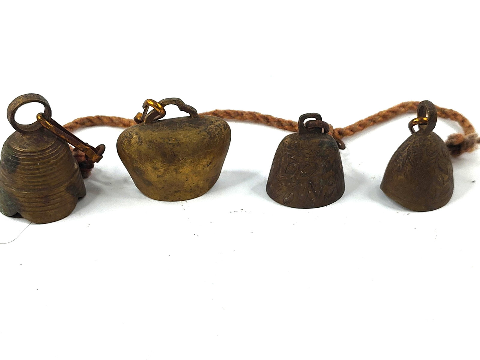 Set 4 Vtg Indian Brass Bells of Sarna: An assortment of four cast brass bells, identified as Bells of Sarna, manufactured in India. The collection features various decorative motifs, including one bell with horizontal concentric ribbing, t