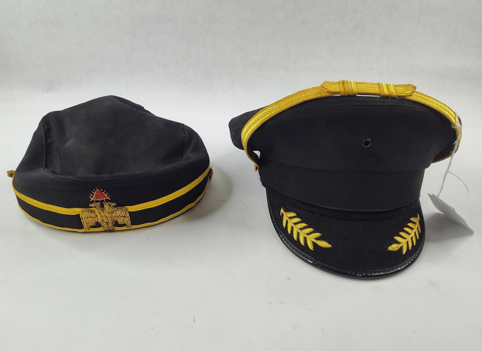Pair US Masonic & Officer Visor Caps: This lot features two pieces of American fraternal uniform headgear. The first item is a black ribbed fabric pillbox style cap associated with the 32nd Degree of the Ancient and Accepted Scottish Rite
