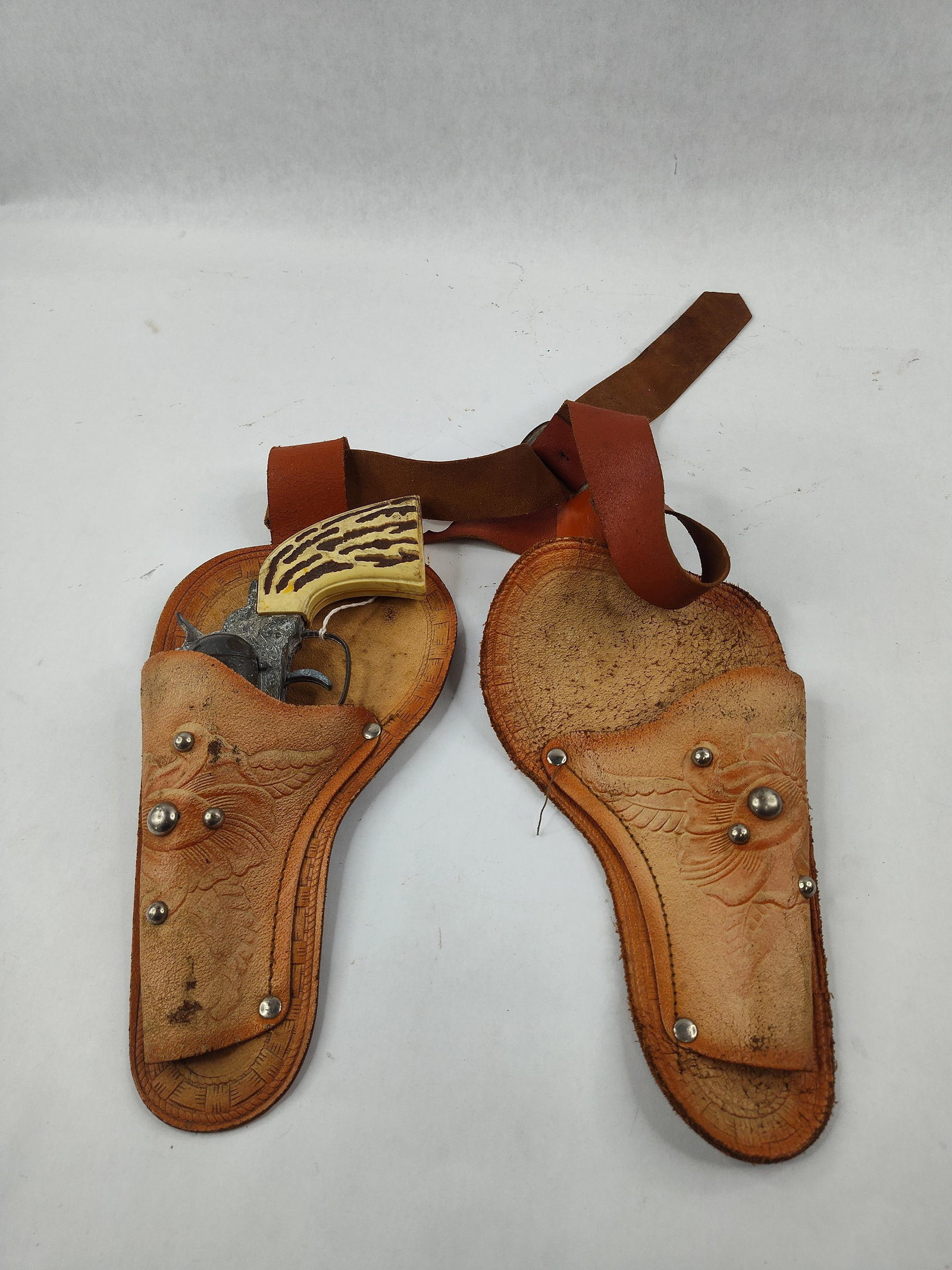 Kusan Die-Cast Cap Gun & Double Holster: A single-action style revolver toy cap gun manufactured by Kusan Inc. of Nashville, Tennessee. The toy gun is constructed from die-cast metal and features cast-in scrollwork and floral engraving