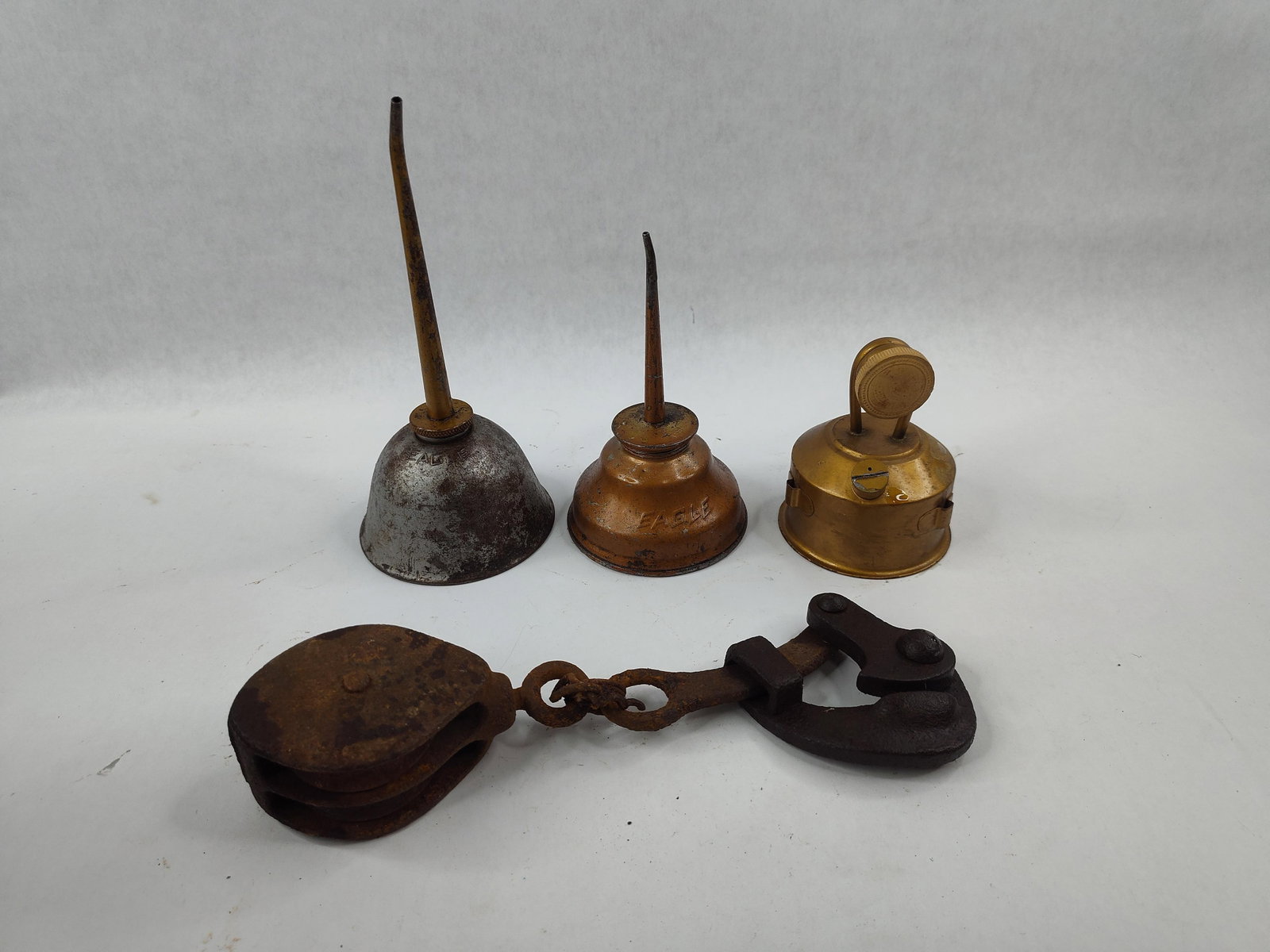 4 Vtg Eagle Oil Cans & Wire Stretcher: This lot consists of four industrial and agricultural tools, including three assorted hand-pump oilers and one heavy-duty wire stretcher tool. Two of the oilers are manufactured by the Eagle Manufactu