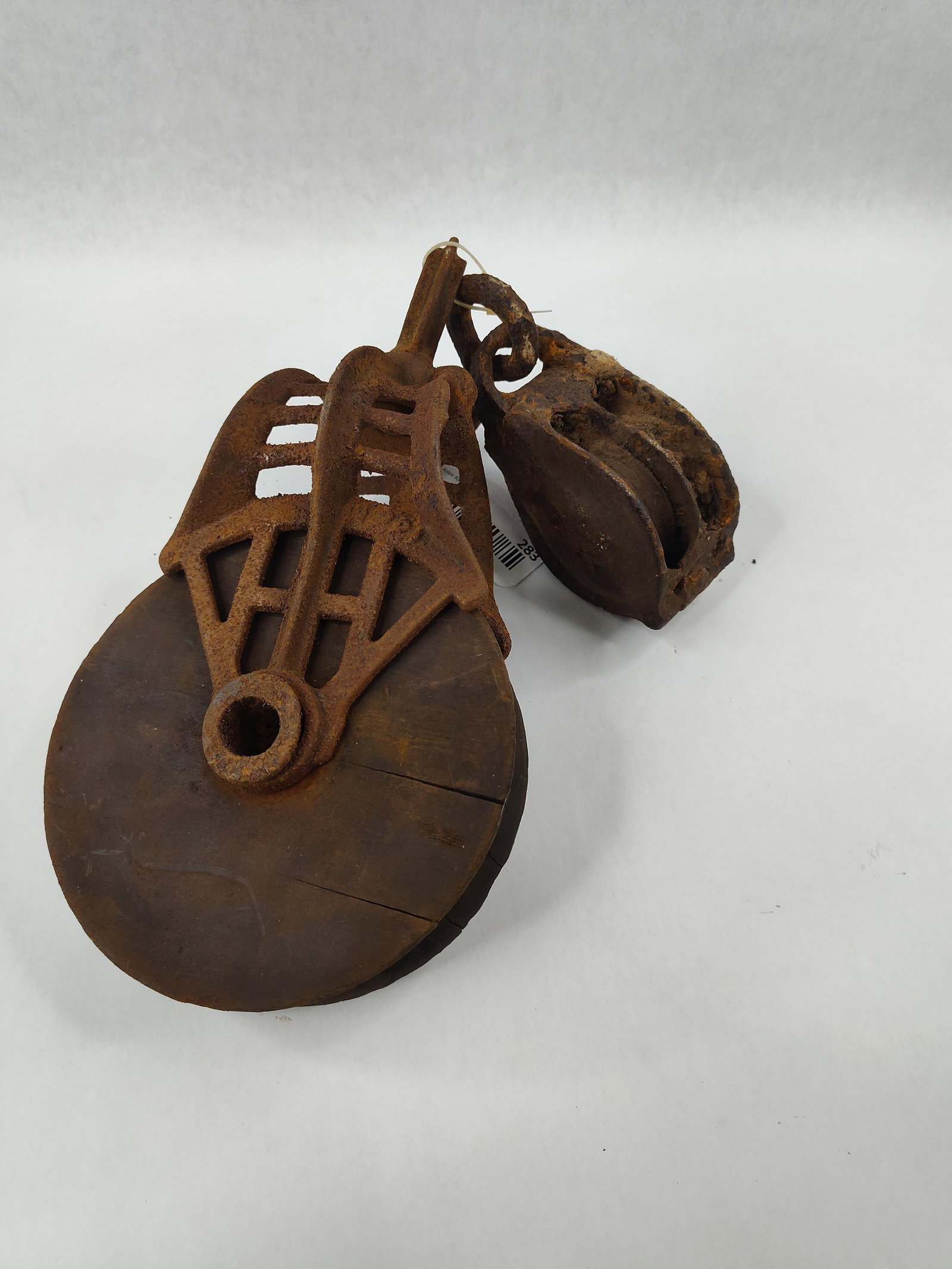 Pair Antique Cast Iron & Wood Pulleys: This lot features two antique industrial pulleys typical of American agricultural and warehouse equipment from the late 19th to early 20th century. The larger item is a hay pulley manufactured by F.E.