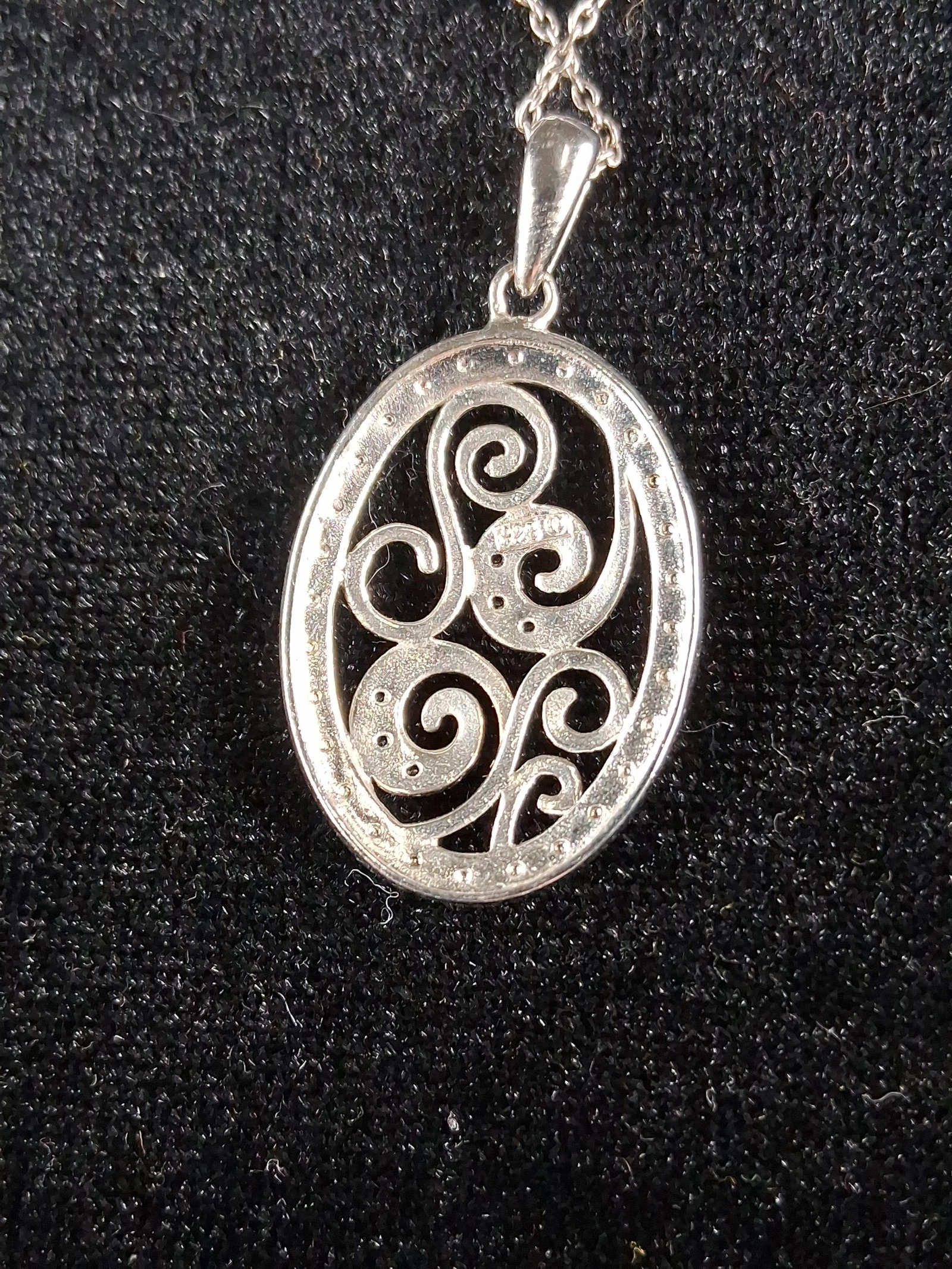 Str. Diamond Swirls Pendant Necklace: This sterling silver pendant necklace features an oval openwork design containing interlocking scroll and swirl motifs. The textured surfaces of the scrolls are set with multiple small, round-cut