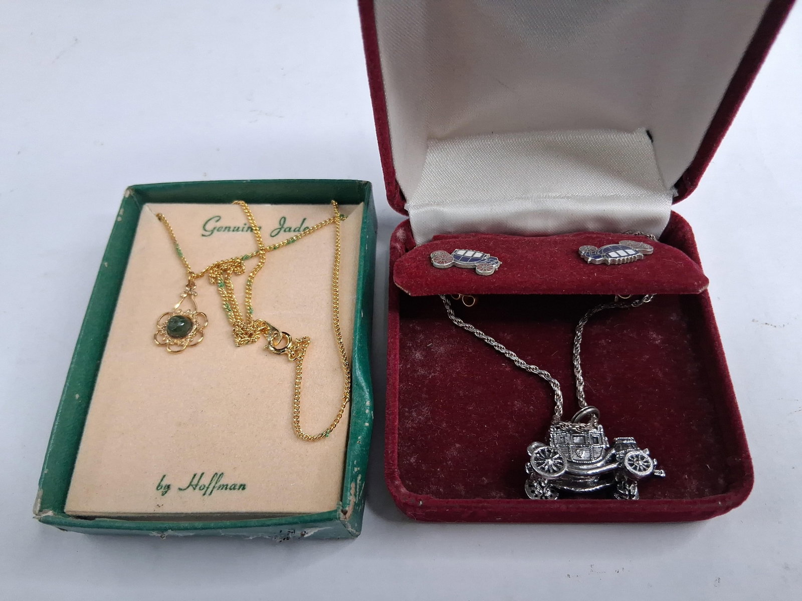 Hoffman Jade Pendant & Stagecoach Set: This lot features two jewelry items in their original presentation boxes. The first item is a Hoffman pendant necklace featuring a circular gold-tone openwork floral pendant. The center of the pendant