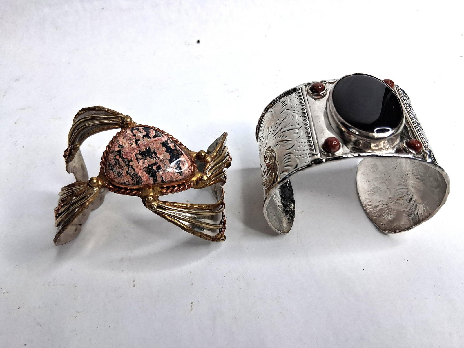 Two Artisan Mixed-Metal Stone-Set Cuffs: A lot featuring two statement cuff bracelets accented with large natural stone cabochons. The first is a mixed-metal open-back cuff featuring silver-tone, copper-tone, and brass-tone components. It di