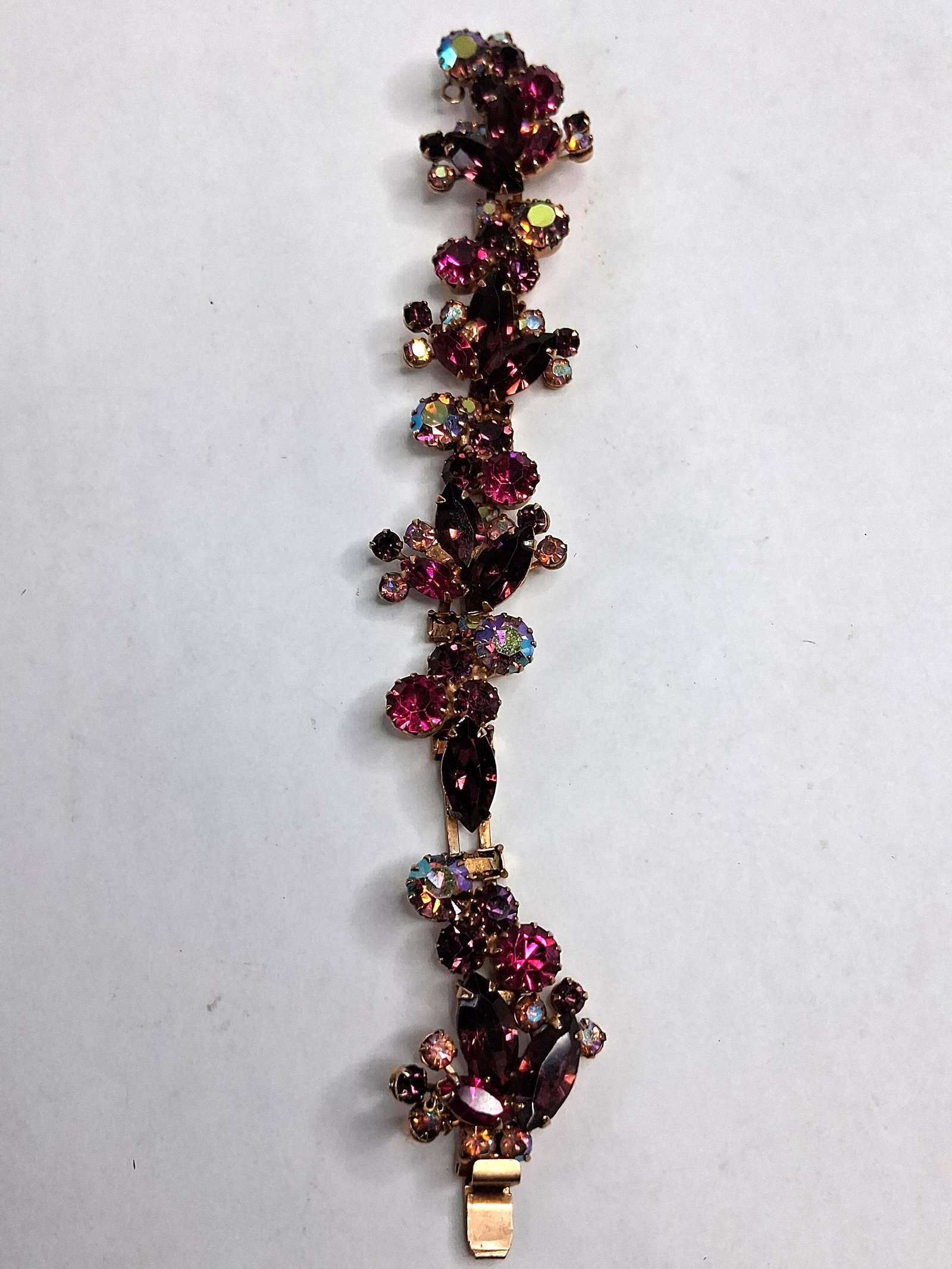 Weiss Purple & Fuchsia Cluster Bracelet: A costume jewelry bracelet manufactured by Weiss. The piece is crafted from gold-tone base metal and features articulated cluster links. The design incorporates a variety of glass rhinestones, includi
