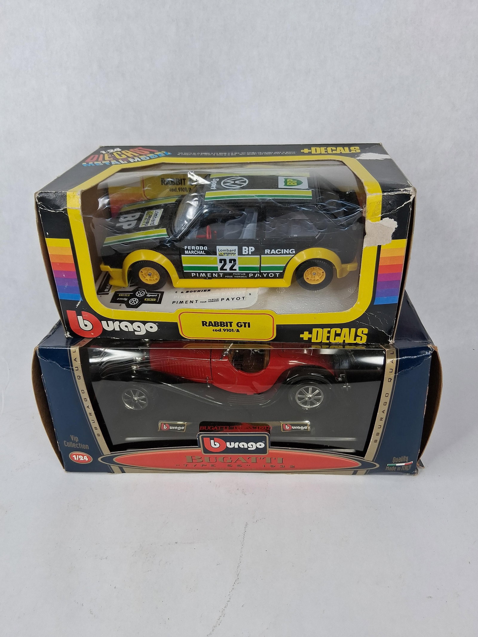 Pair Bburago 1/24 Die-Cast VW & Bugatti: Two 1/24 scale die-cast metal model cars manufactured in Italy by Bburago. Both models are presented in their original manufacturer window boxes. The first model is a Volkswagen Rabbit GTI (Golf Mk1),