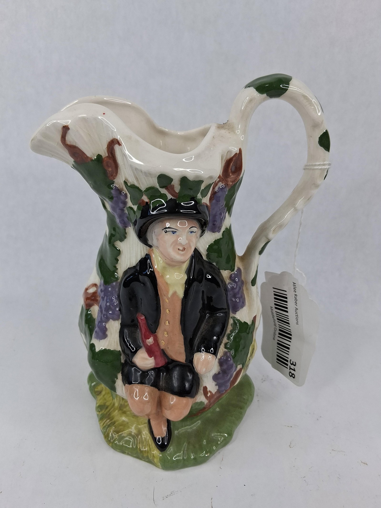 Mona Fair Hebe Ceramic Pitcher 1966: This relief-molded and hand-painted glazed earthenware pitcher is a 20th-century version of the 18th-century Fair Hebe design. The pitcher features a bulbous, textured form with a branch-style handle 