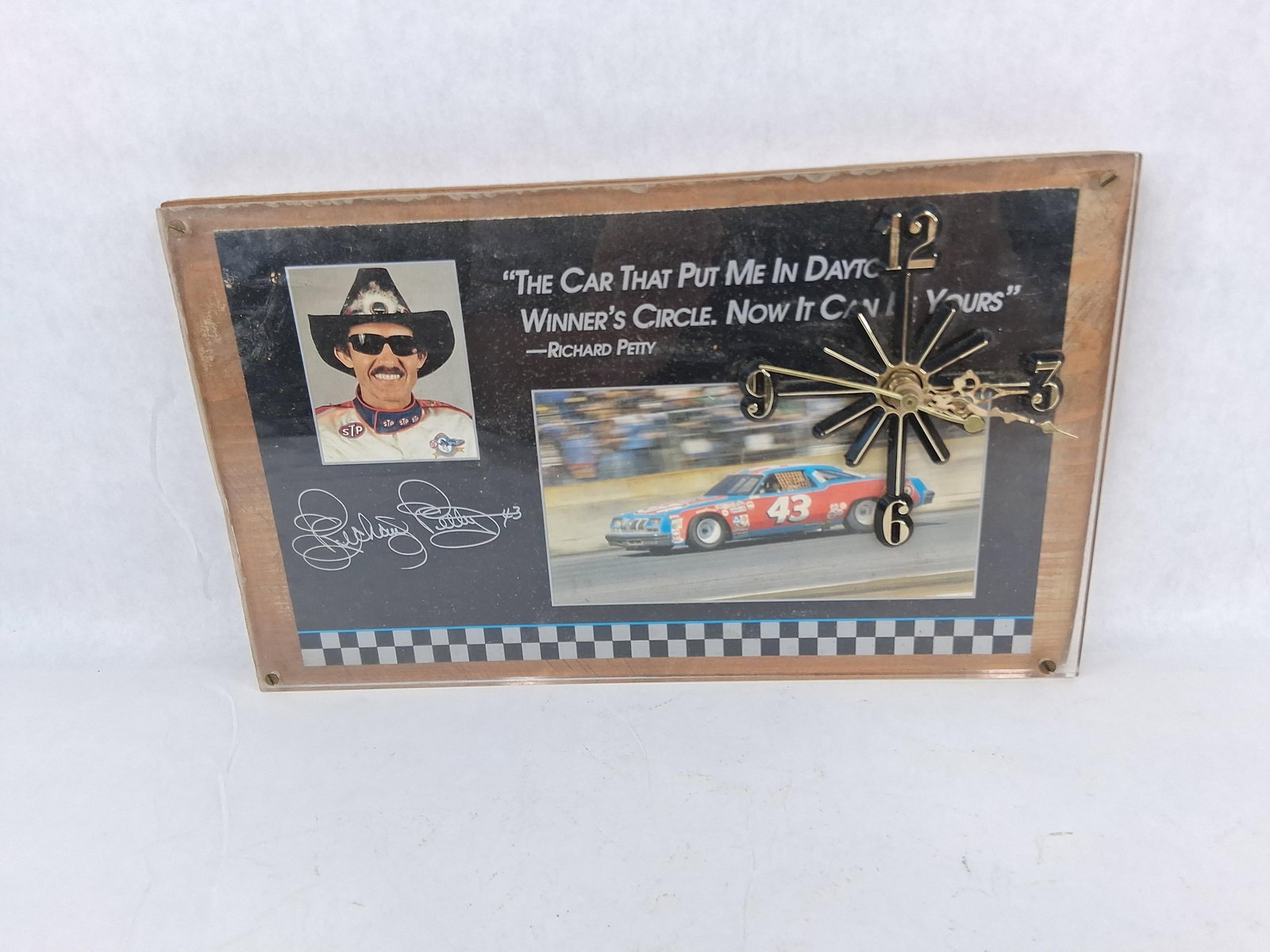 Richard Petty STP #43 Race Car Clock: This wall clock features a commemorative design dedicated to NASCAR legend Richard Petty. The piece consists of a rectangular wooden base topped with a printed graphic display and a clear acrylic