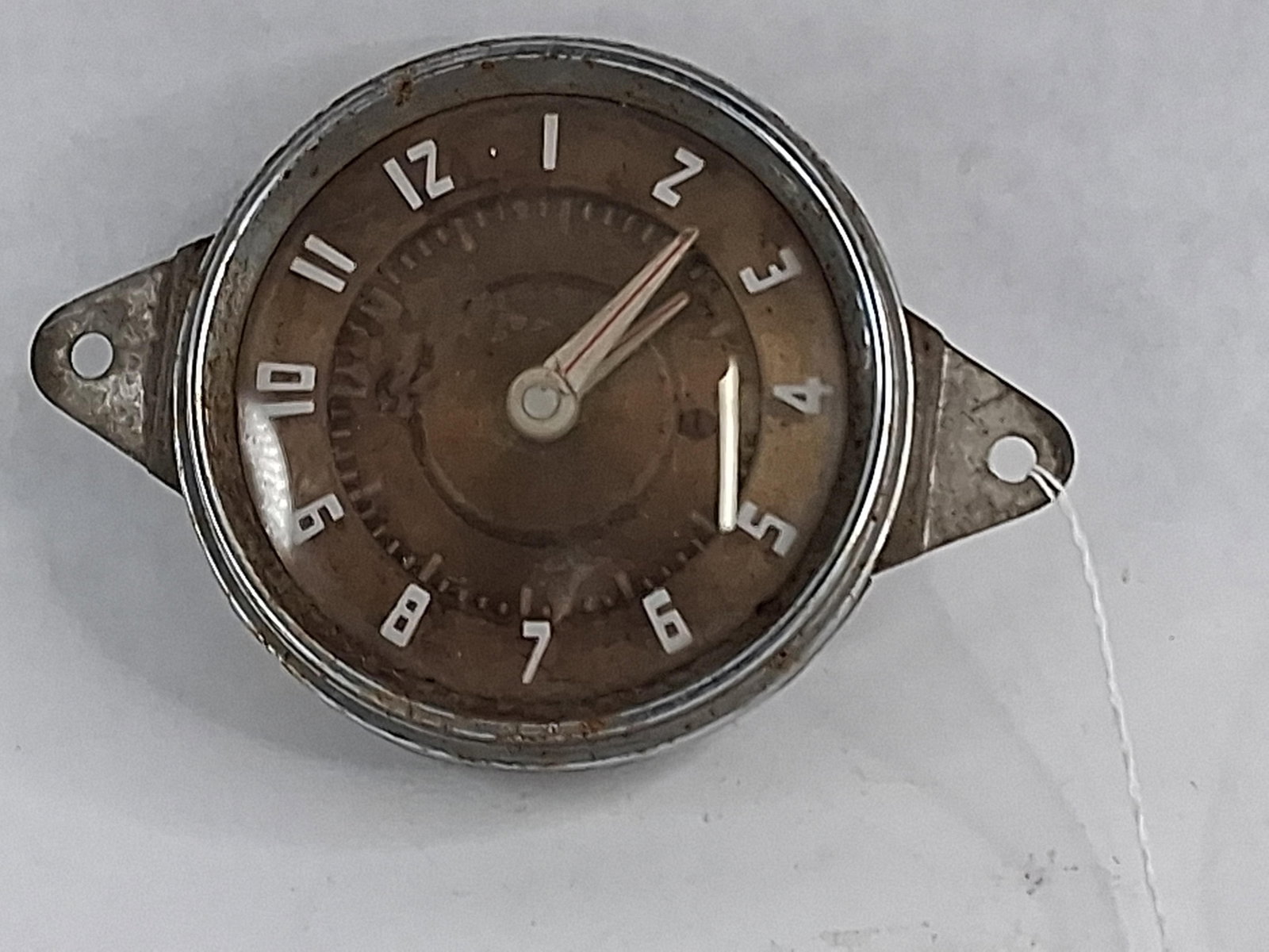 1941-1948 Nash Electric Dashboard Clock: A factory electric dashboard clock for Nash 600 and Ambassador models, manufactured between 1941 and 1948. The unit is housed in a circular metal casing featuring two integrated triangular mounting