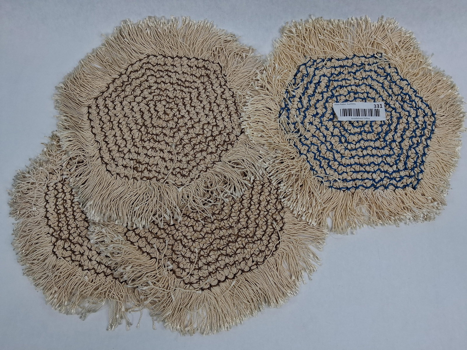 Set 4 Handmade Loom Woven Fringed Mats: A set of four circular handmade mats featuring a loom-woven pinwheel or wagon wheel construction. Each mat is composed of thick cream-colored cord, likely cotton or a cotton-synthetic blend. The cord 