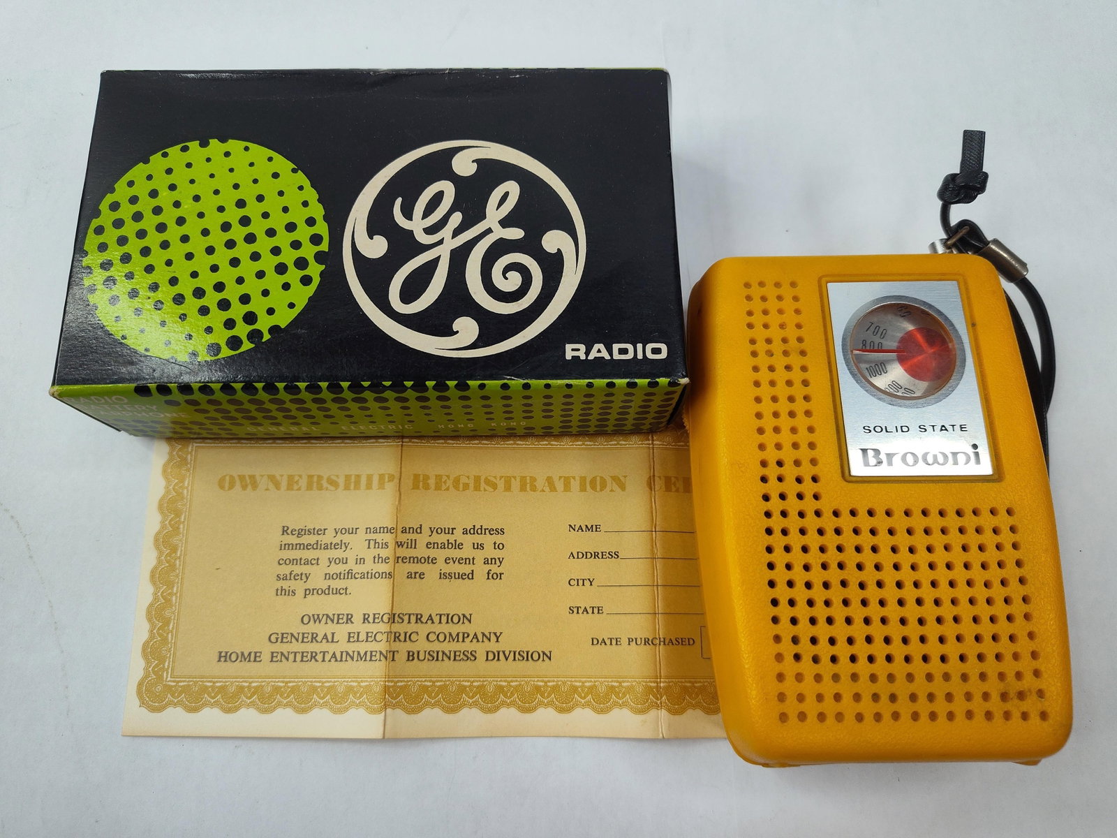 GE P-1758 Browni Transistor Radio & Box: This General Electric portable transistor radio, model P-1758, features a textured yellow plastic cabinet and is branded as the Browni model. The front of the unit includes a circular analog tuning