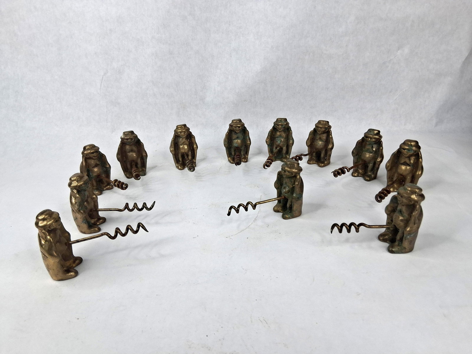 11 Vtg Brass Naughty Novelty Corkscrews: This collection consists of eleven novelty corkscrews. Each item is constructed from a solid cast brass figure depicted as a man wearing a wide-brimmed hat and an open trench coat. A steel corkscrew w