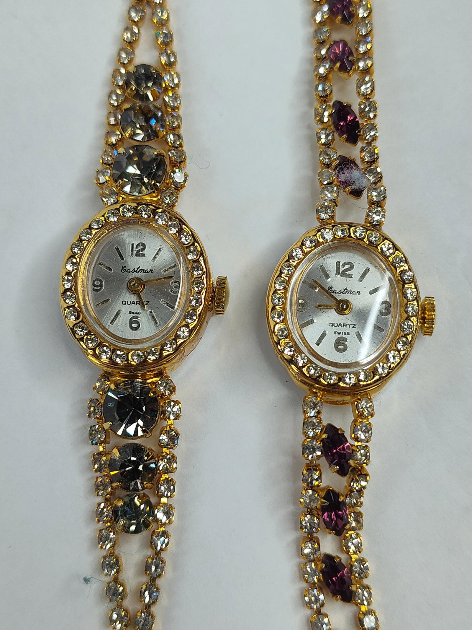Pair Eastman Ladies Cocktail Watches: This lot features a pair of ladies quartz cocktail wristwatches by Eastman. Both timepieces are constructed with gold-tone base metal cases and stainless steel case backs. The silver-tone sunburst